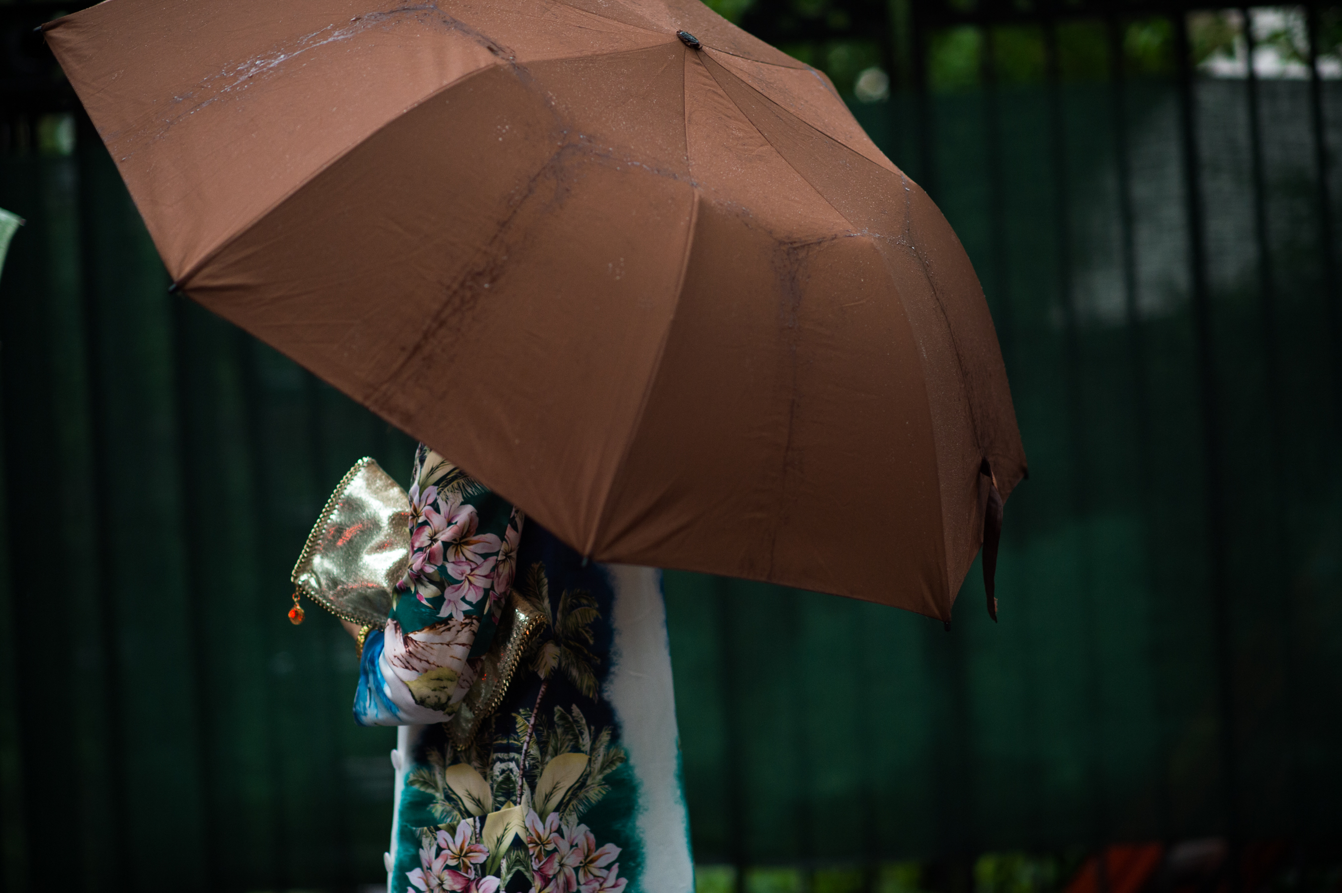 Woman with brown umbrella and chain clutch