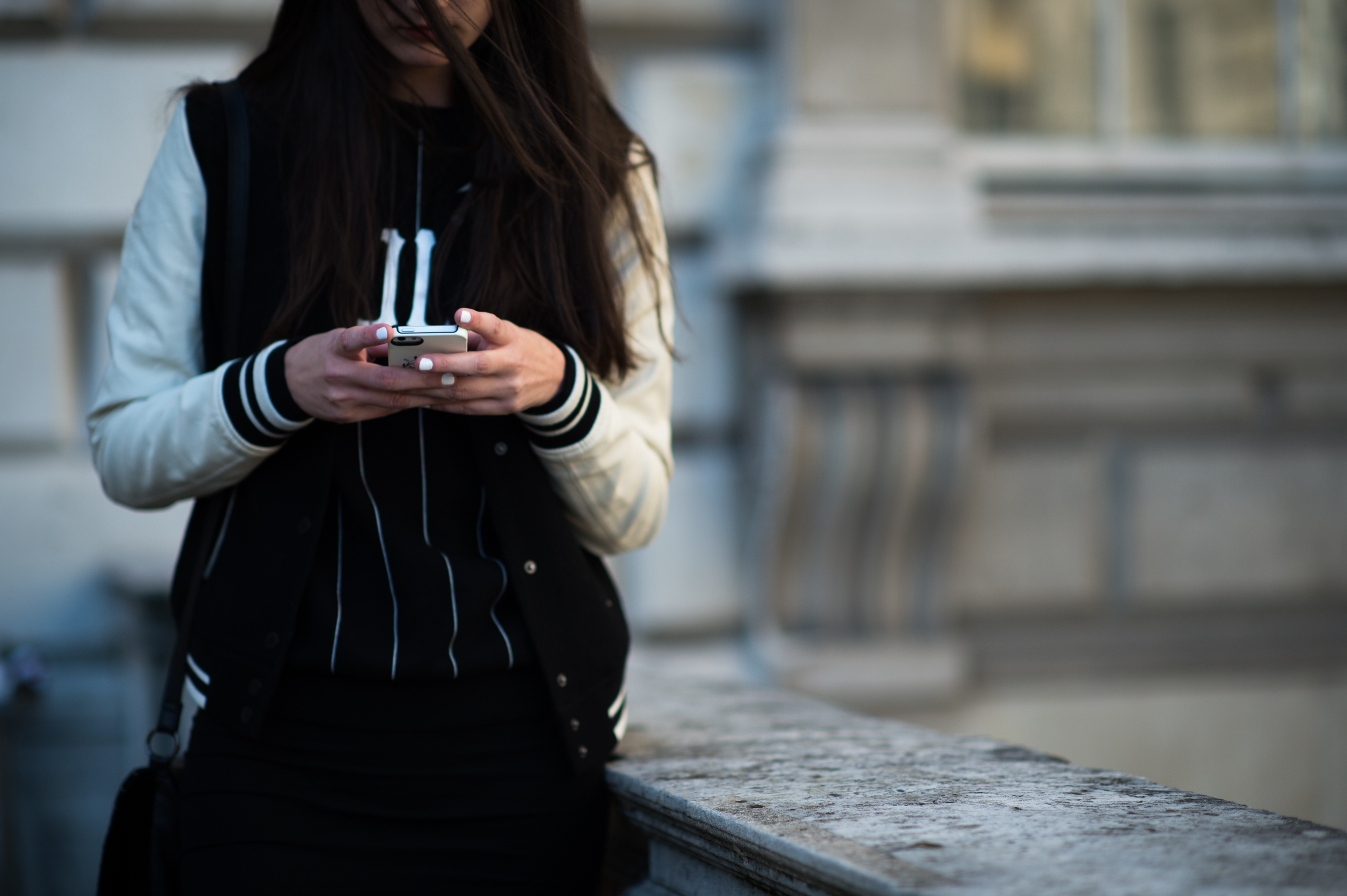 Girl texting in varsity jacket