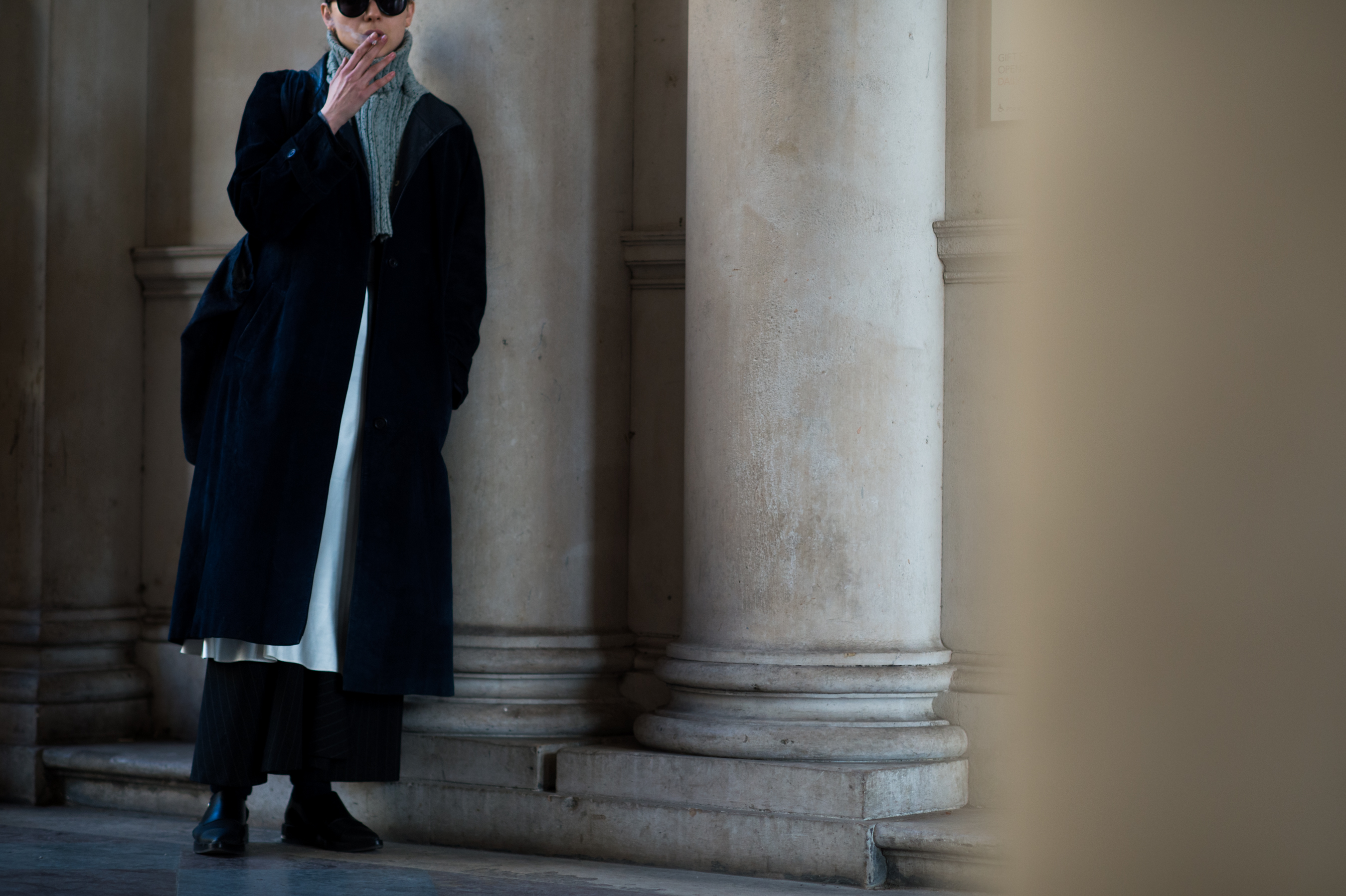 Woman wearing long black coat smoking