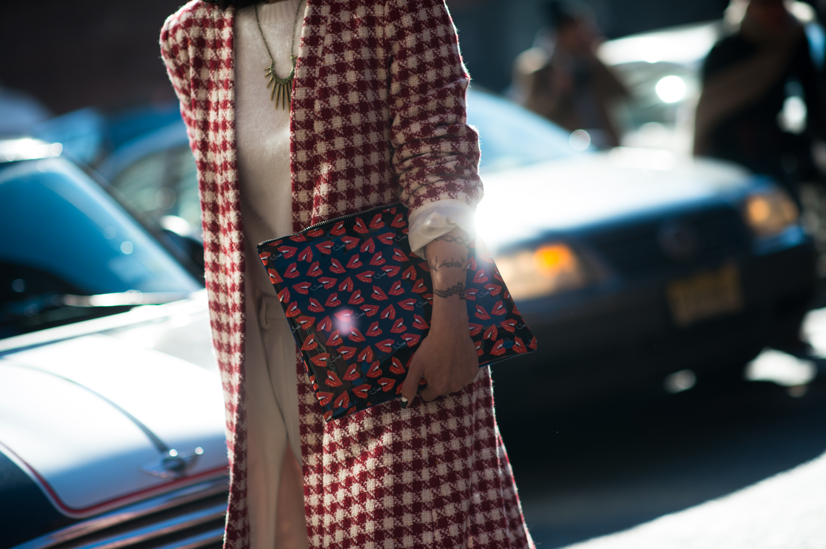 Woman wearing check with lip monogram clutch