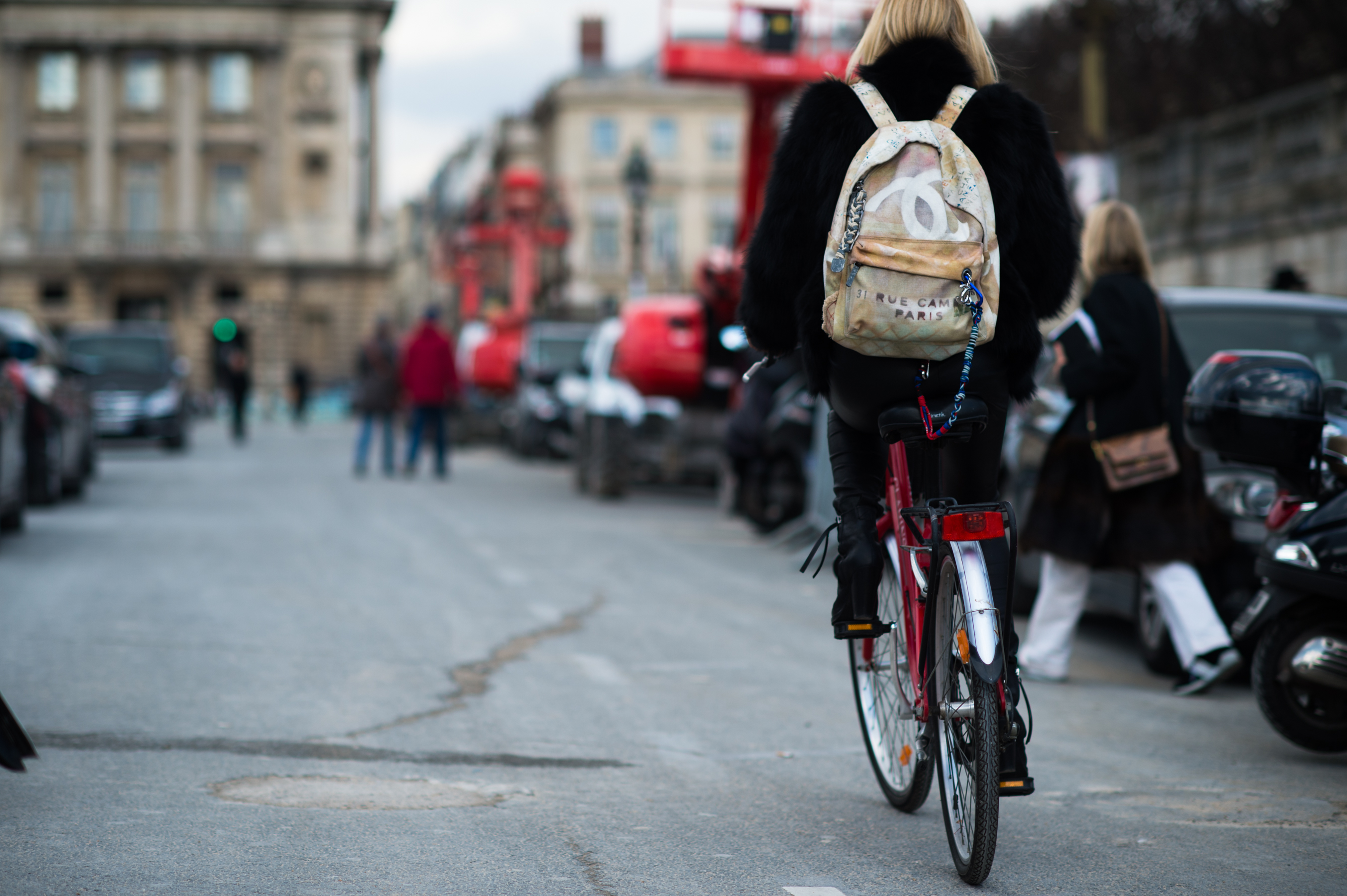 Girl riding a red bike with a Chanel backpack