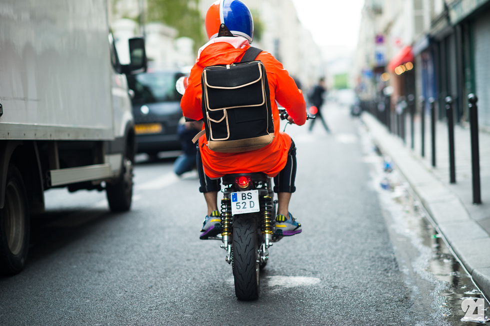 Man riding a tiny scooter wearing orange