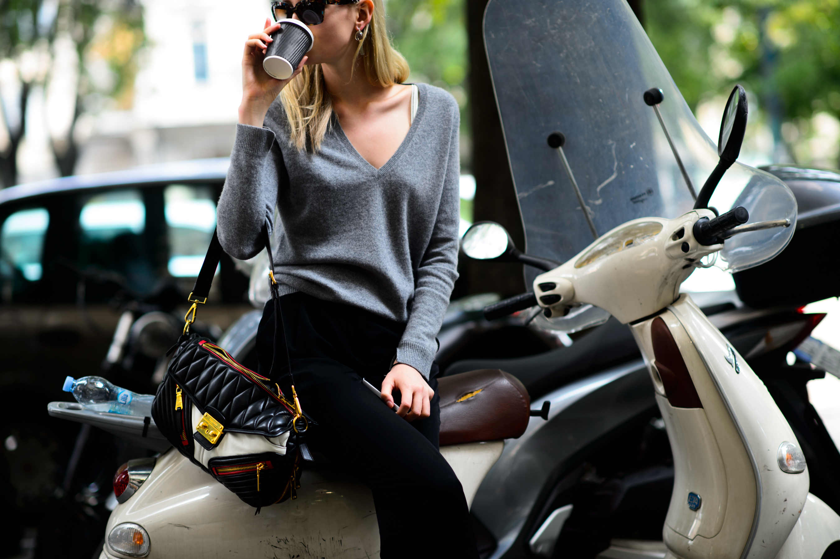 Blonde model drinking her coffee on a Vespa