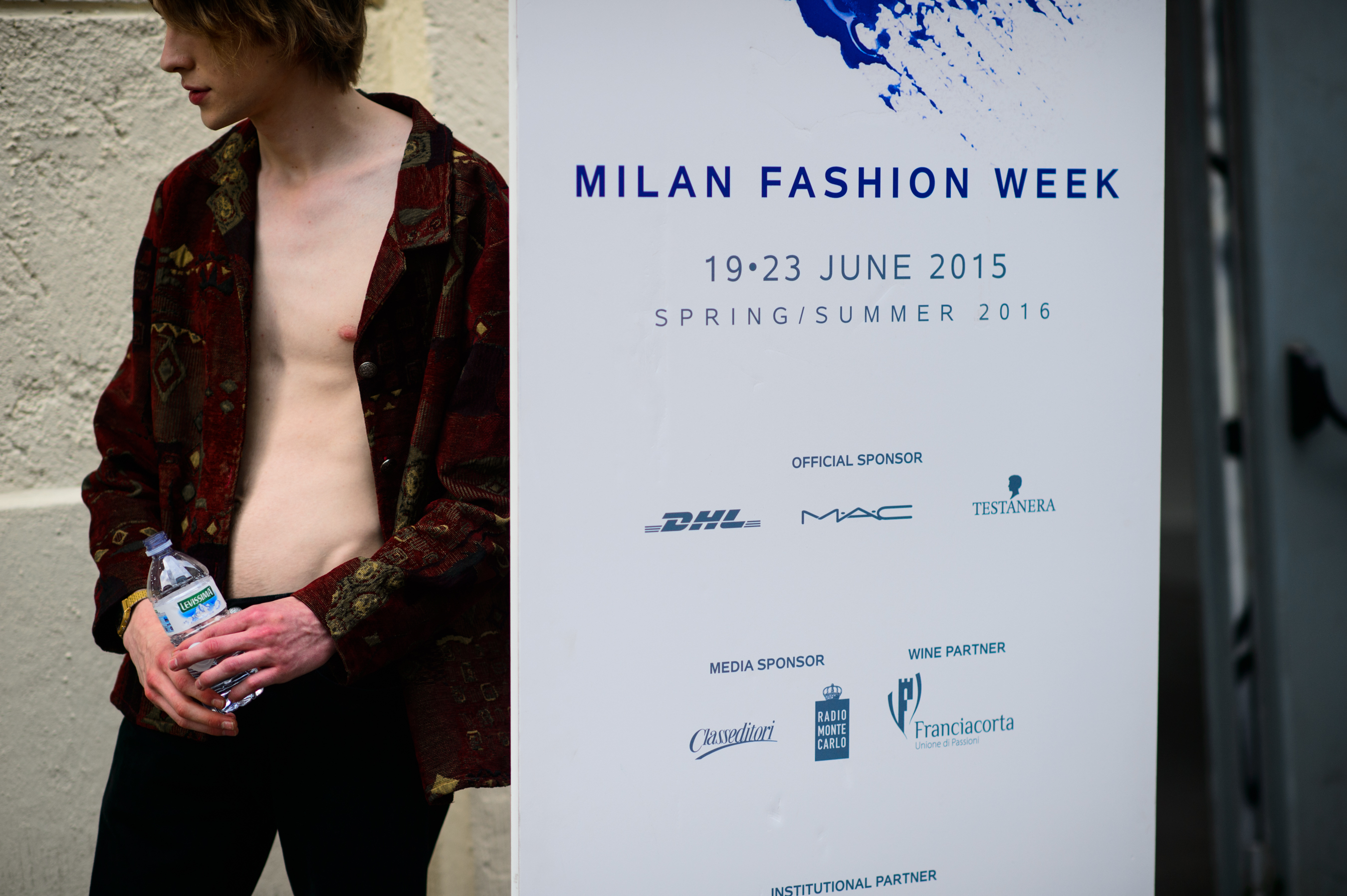 Male model in unbuttoned shirt with a bottle of water before the show
