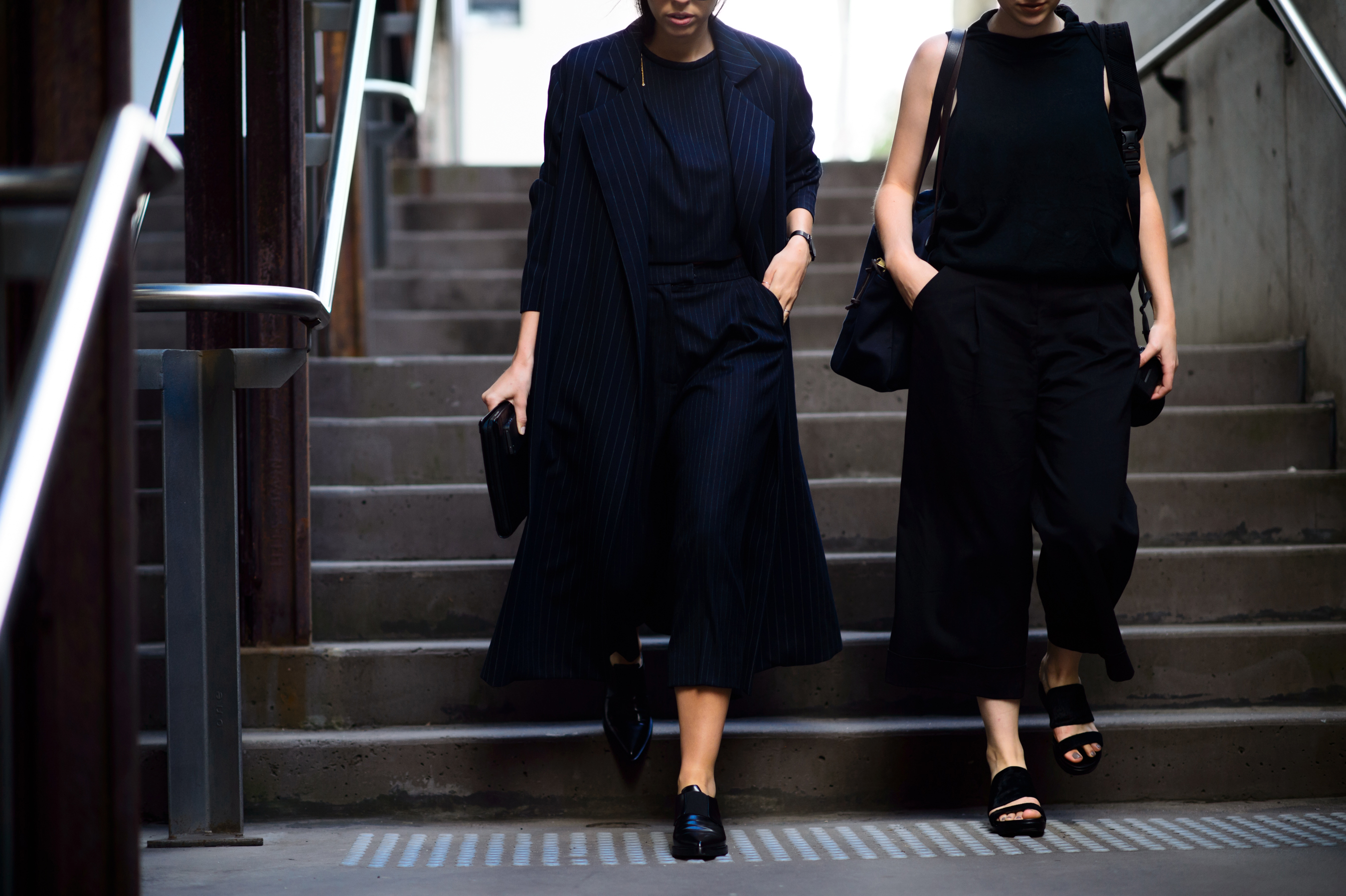 Two women in dark clothed going into the underground crossing