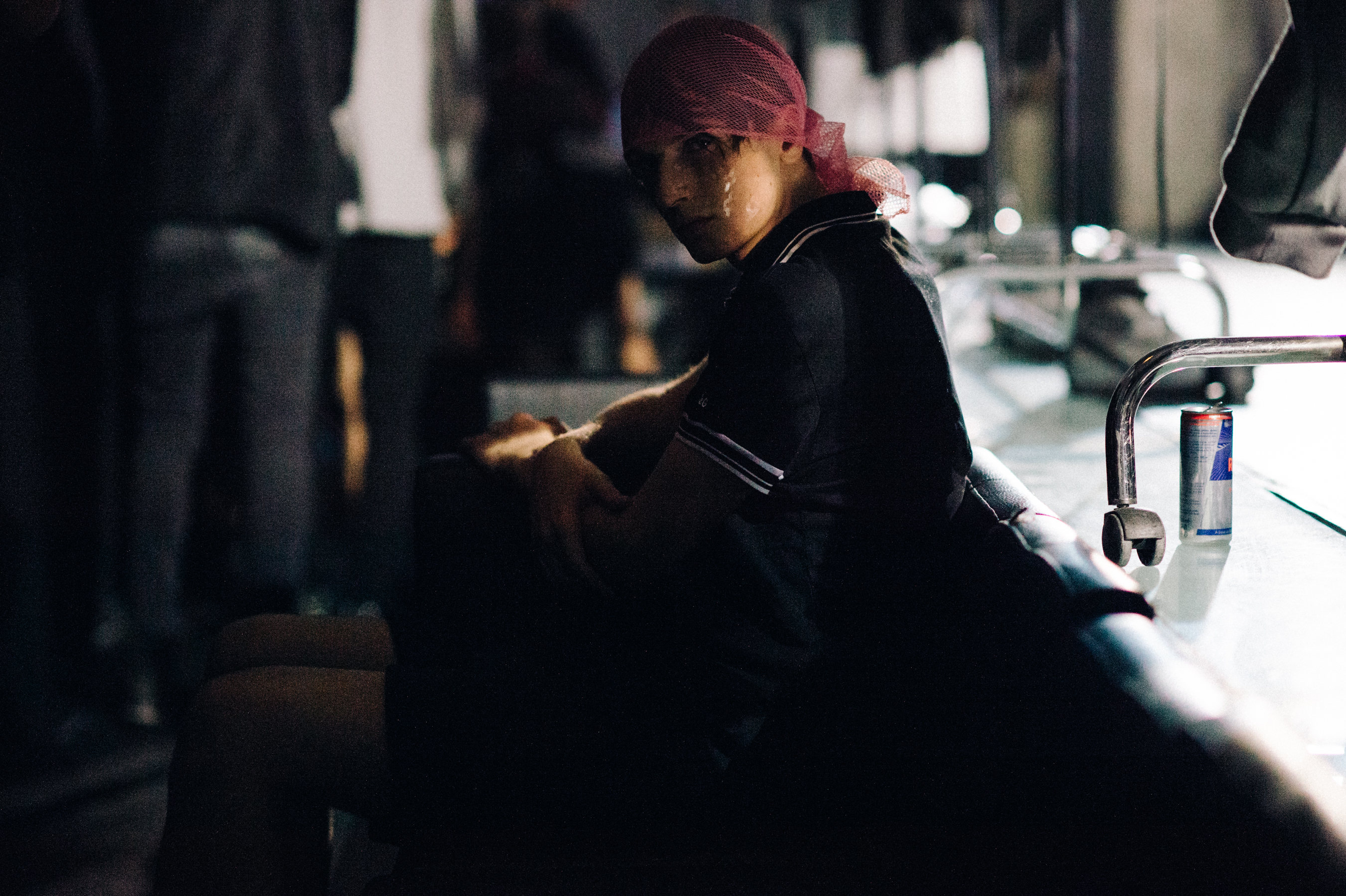 Male model sitting in low light during the rehearsal before the fashion show