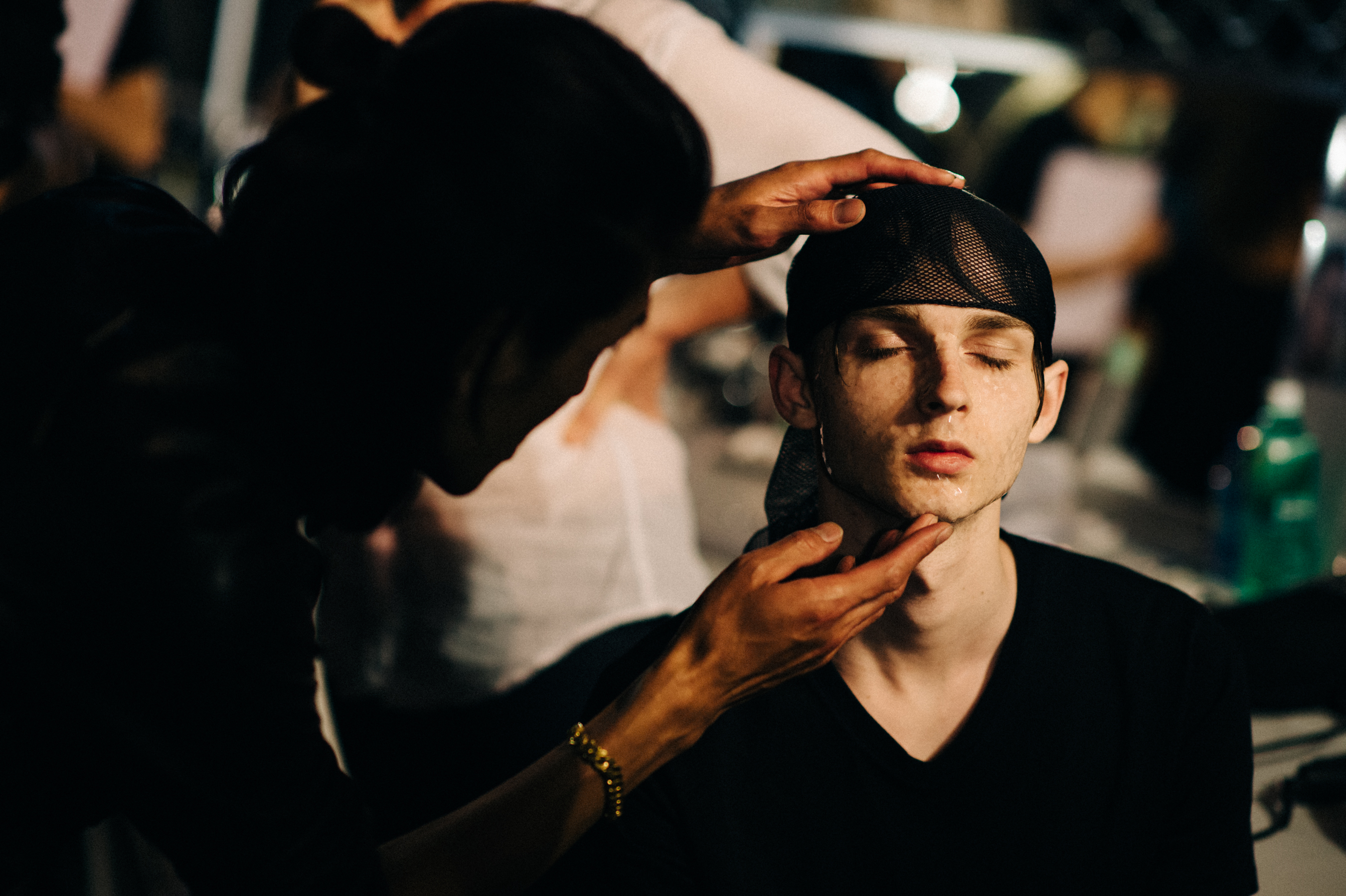 Male model is getting hair and make up done before menswear fashion show