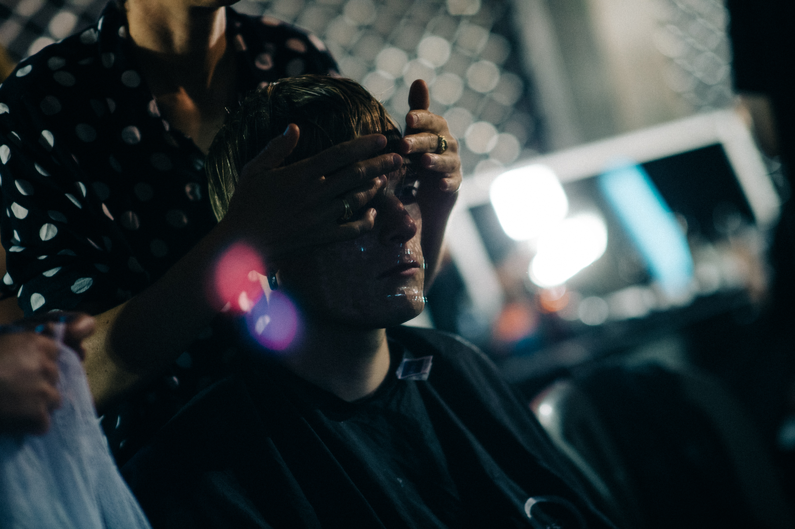 Male model getting hair and make up done before the show