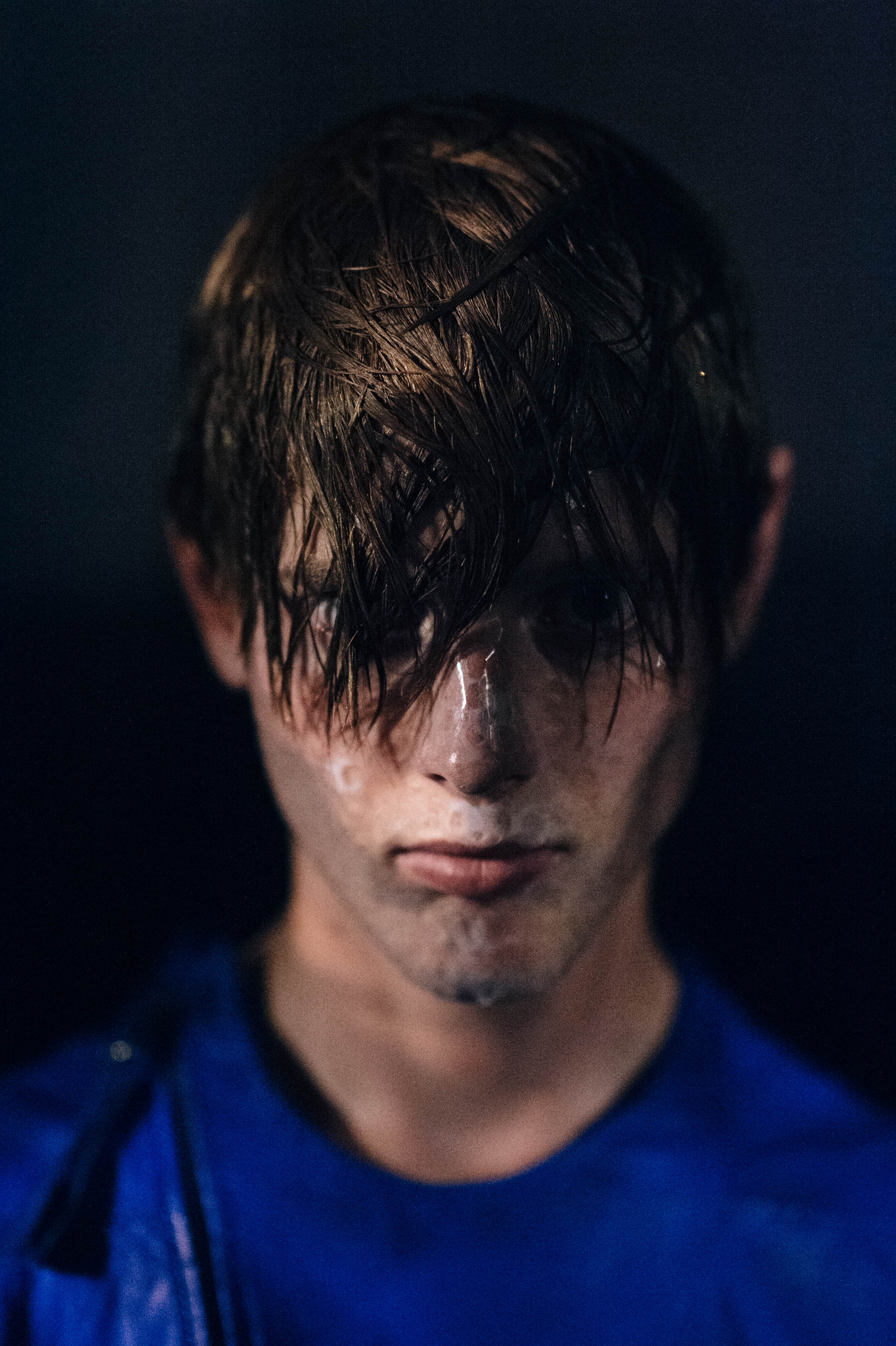 Male model with wet hair covering eyes wearing blue before fashion show