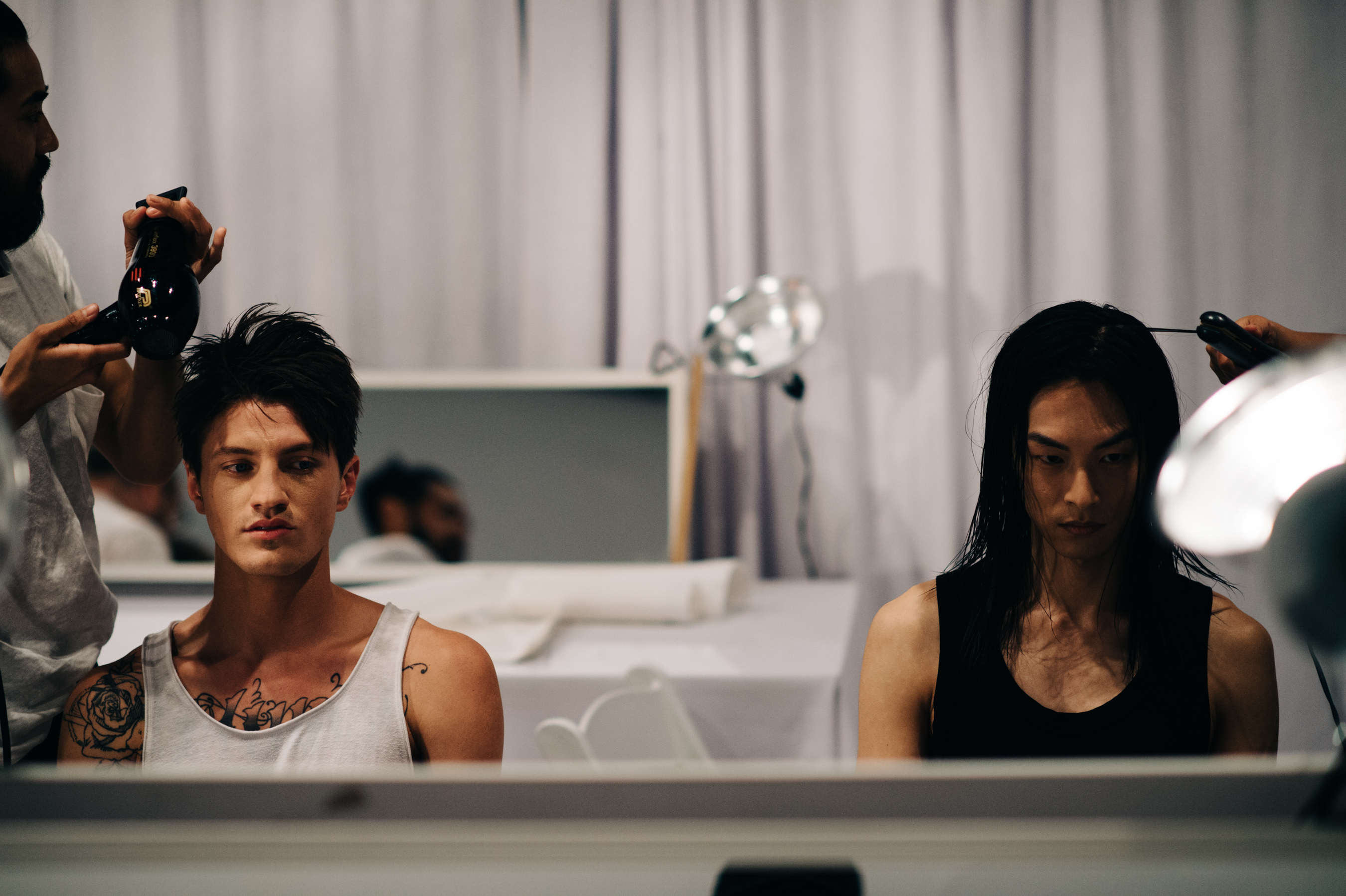 Two male models wearing tank tops before the show