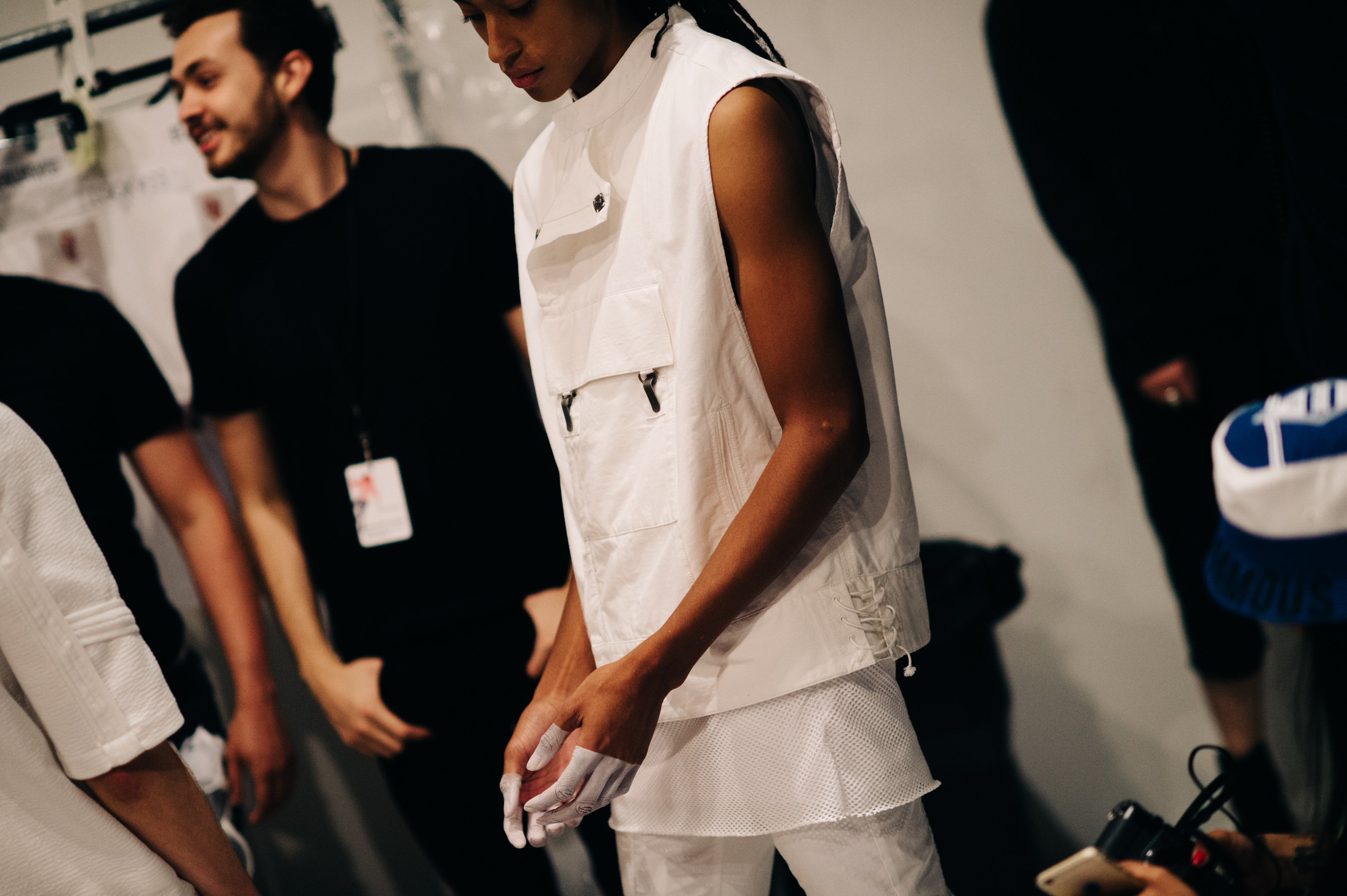 Male model wearing white outfit before the show