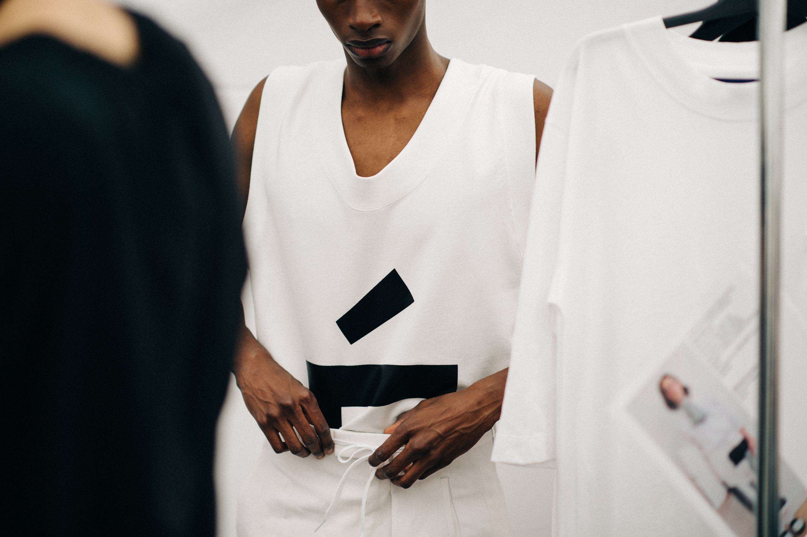 Male model getting dressed in white clothes before the show