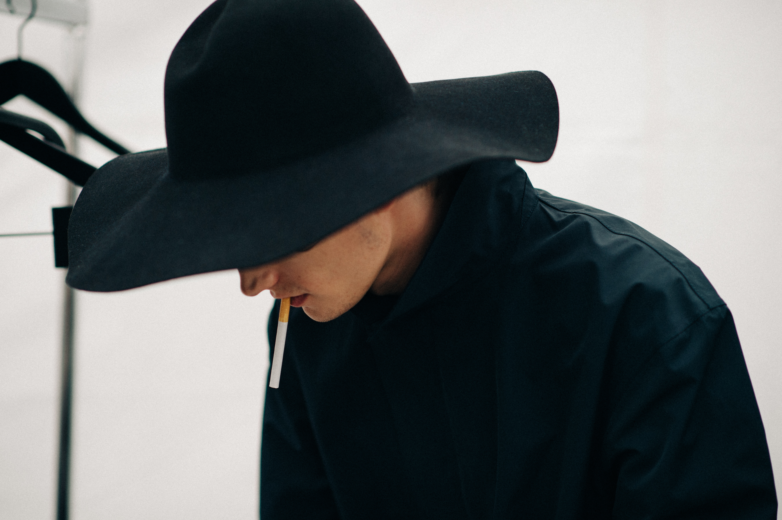 Male model wearing a hat smoking in the dressing room