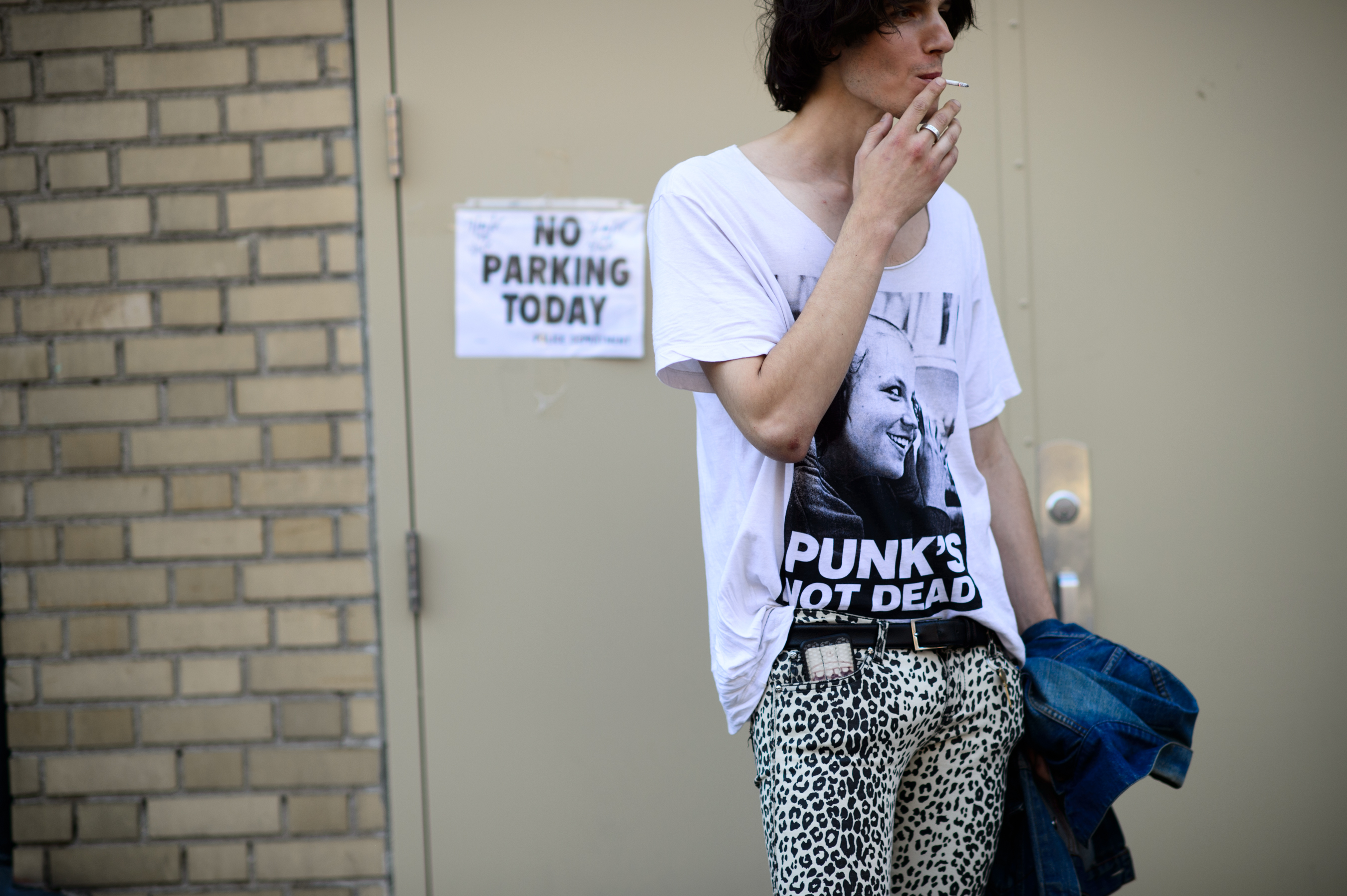 A male model in punk t shirt smoking outside of the show