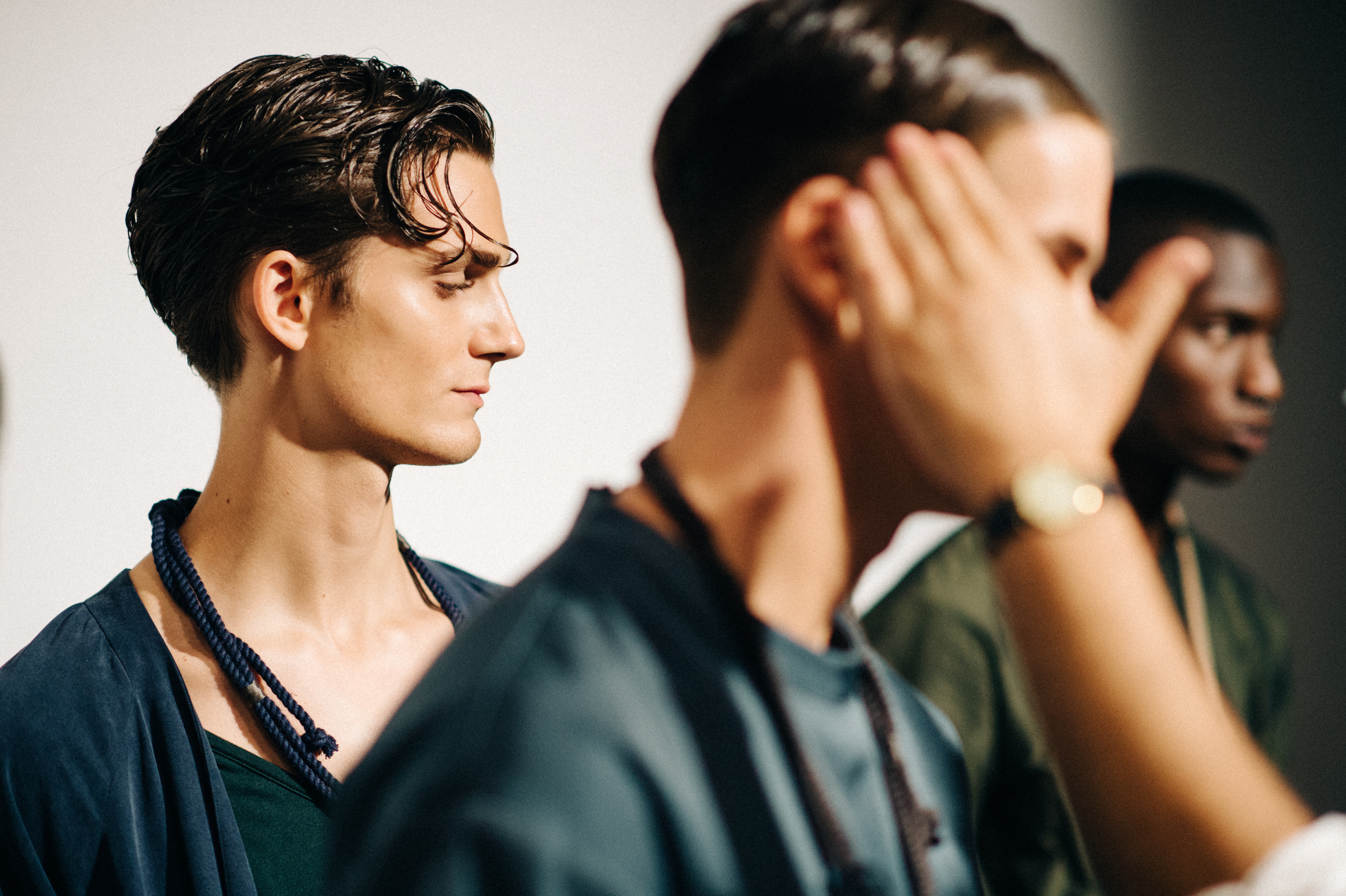 Three male models getting dressed before the show