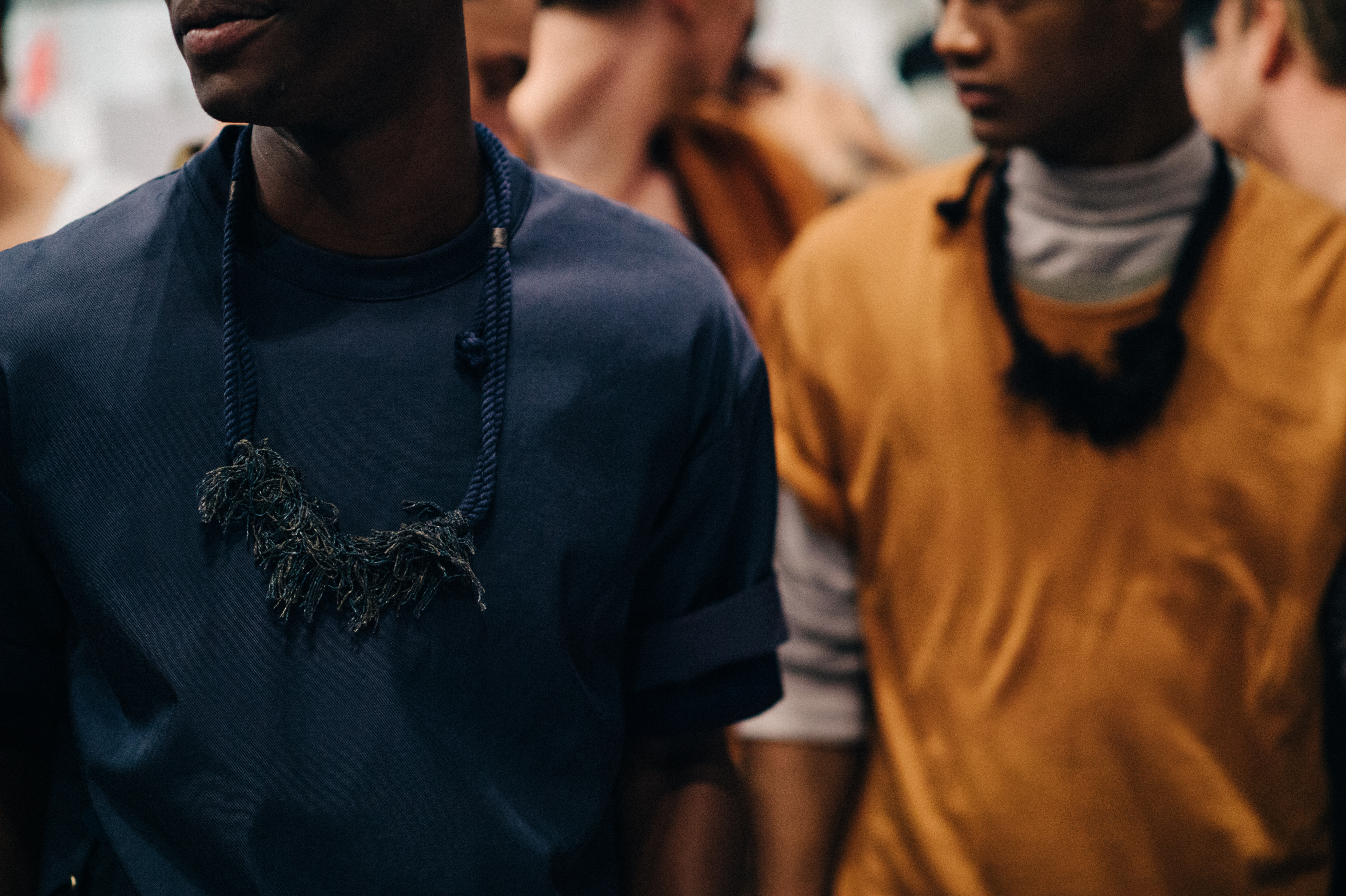 Two male models wearing neck pieces before the show