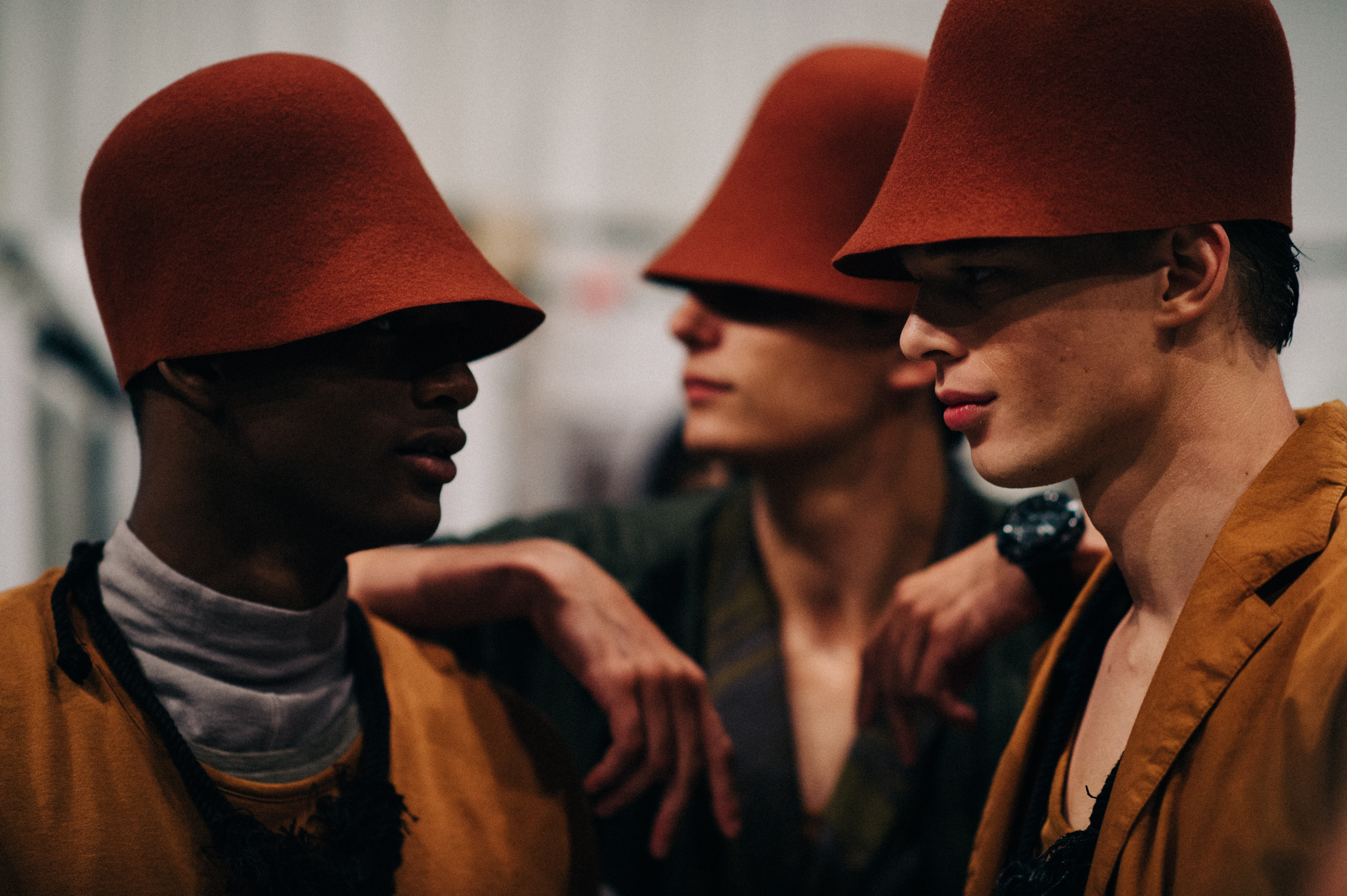 Three male models wearing red hats before the show