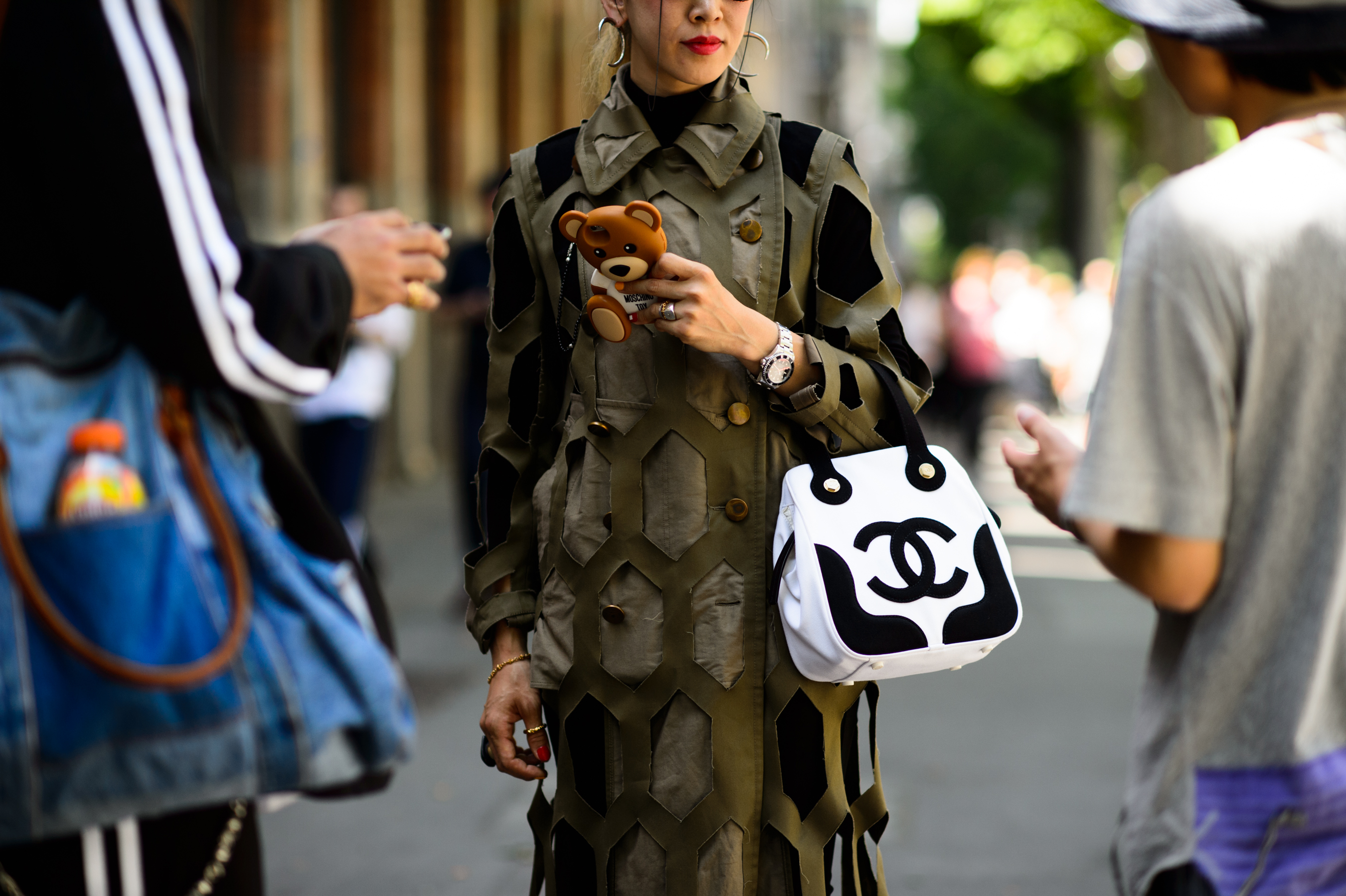 Woman in khaki jacket and white Chanel bag before the show