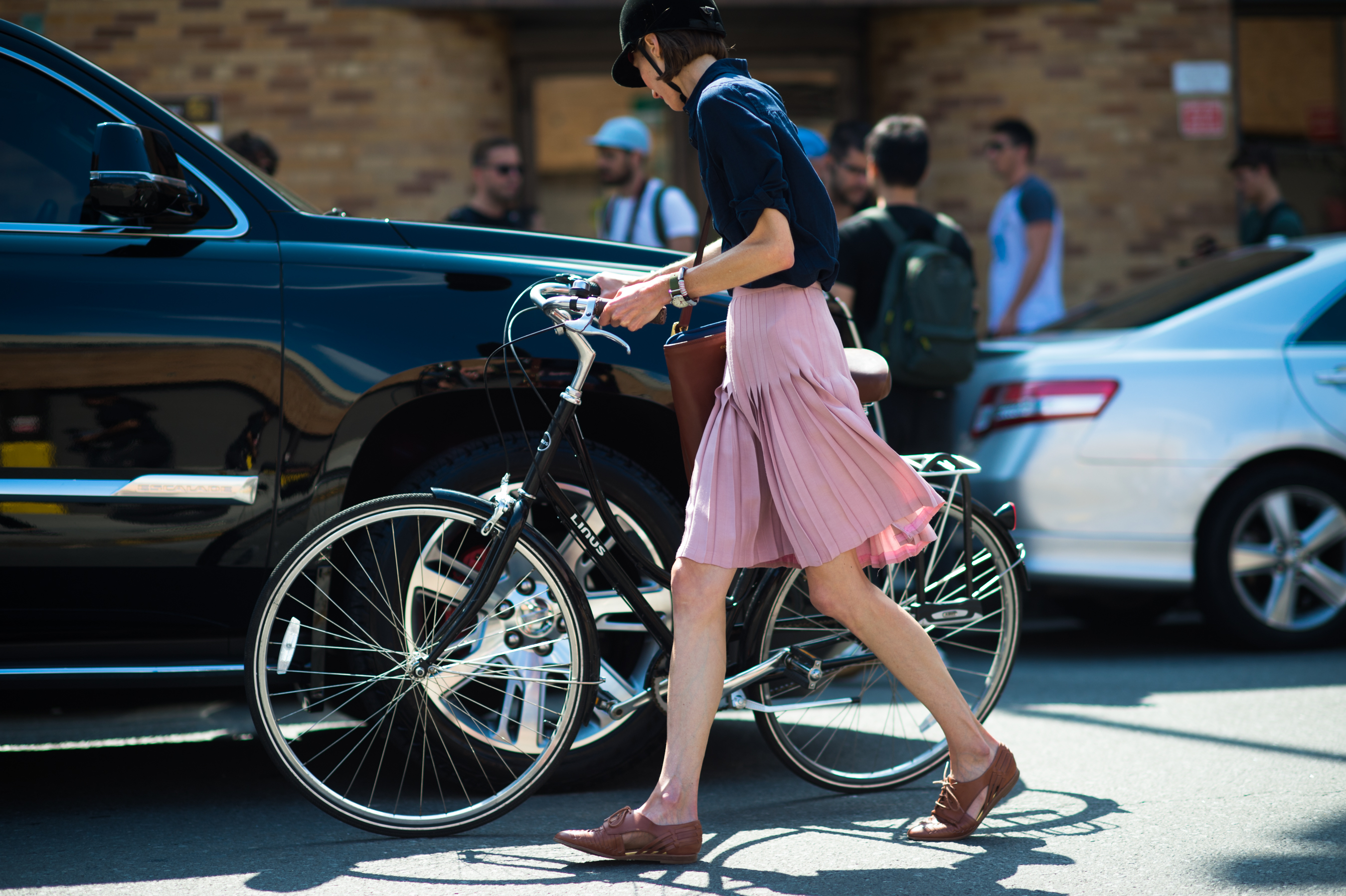 Woman in black helmet and pink skirt getting on the bike