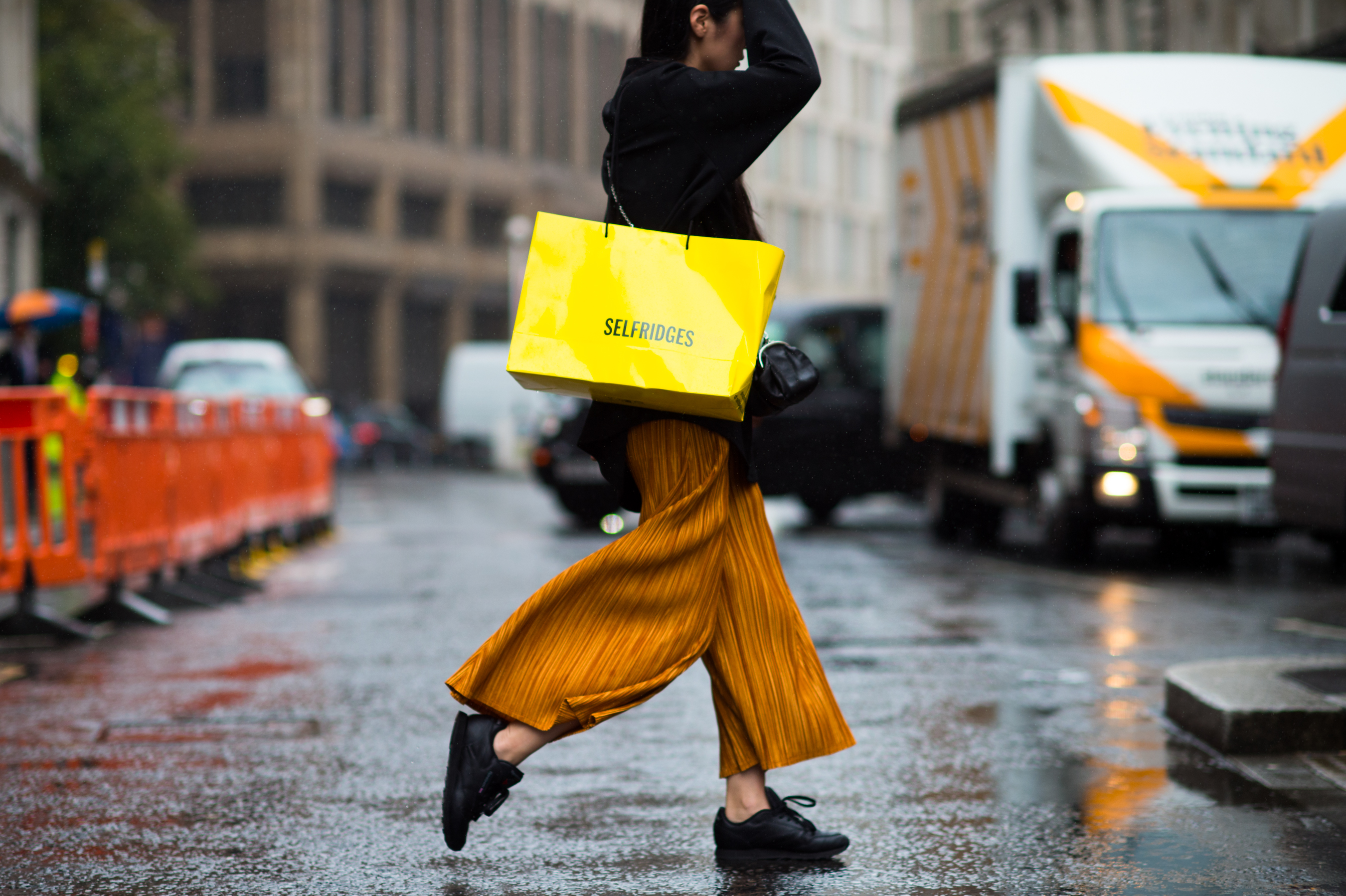 Woman with Selfriges bag and orange pants crossing the street