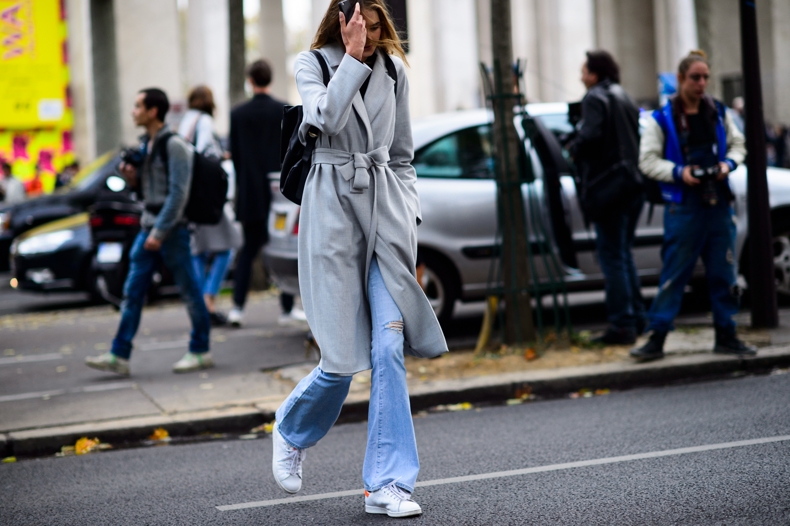 Model crossing the road wearing grey coat