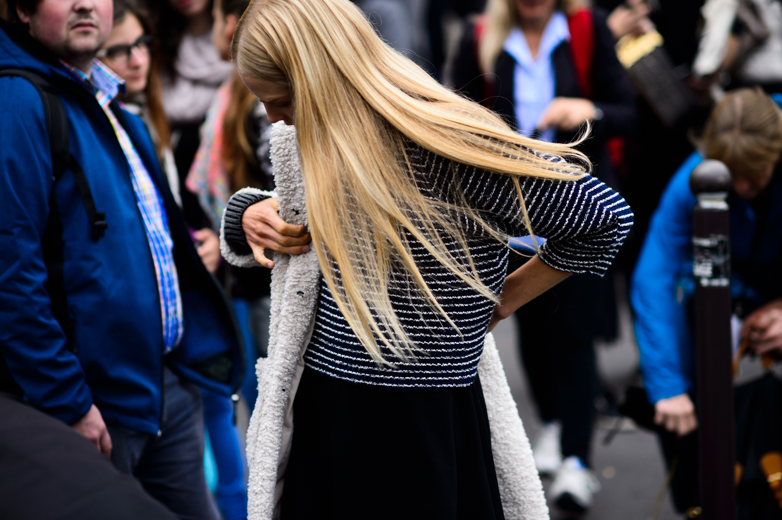 Woman with long white hair putting her coat on