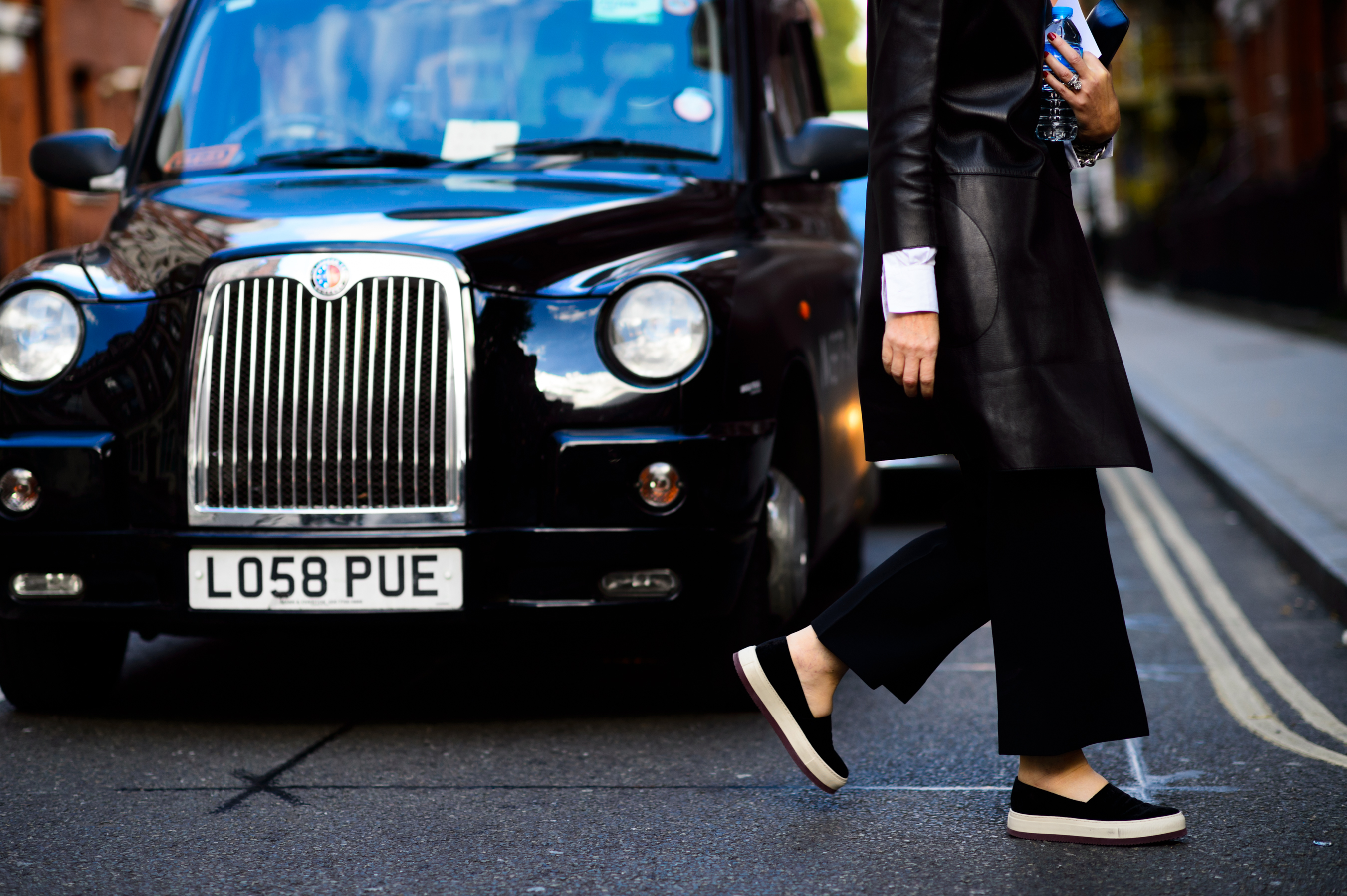 Woman in leather coat crossing the street in front of the cab
