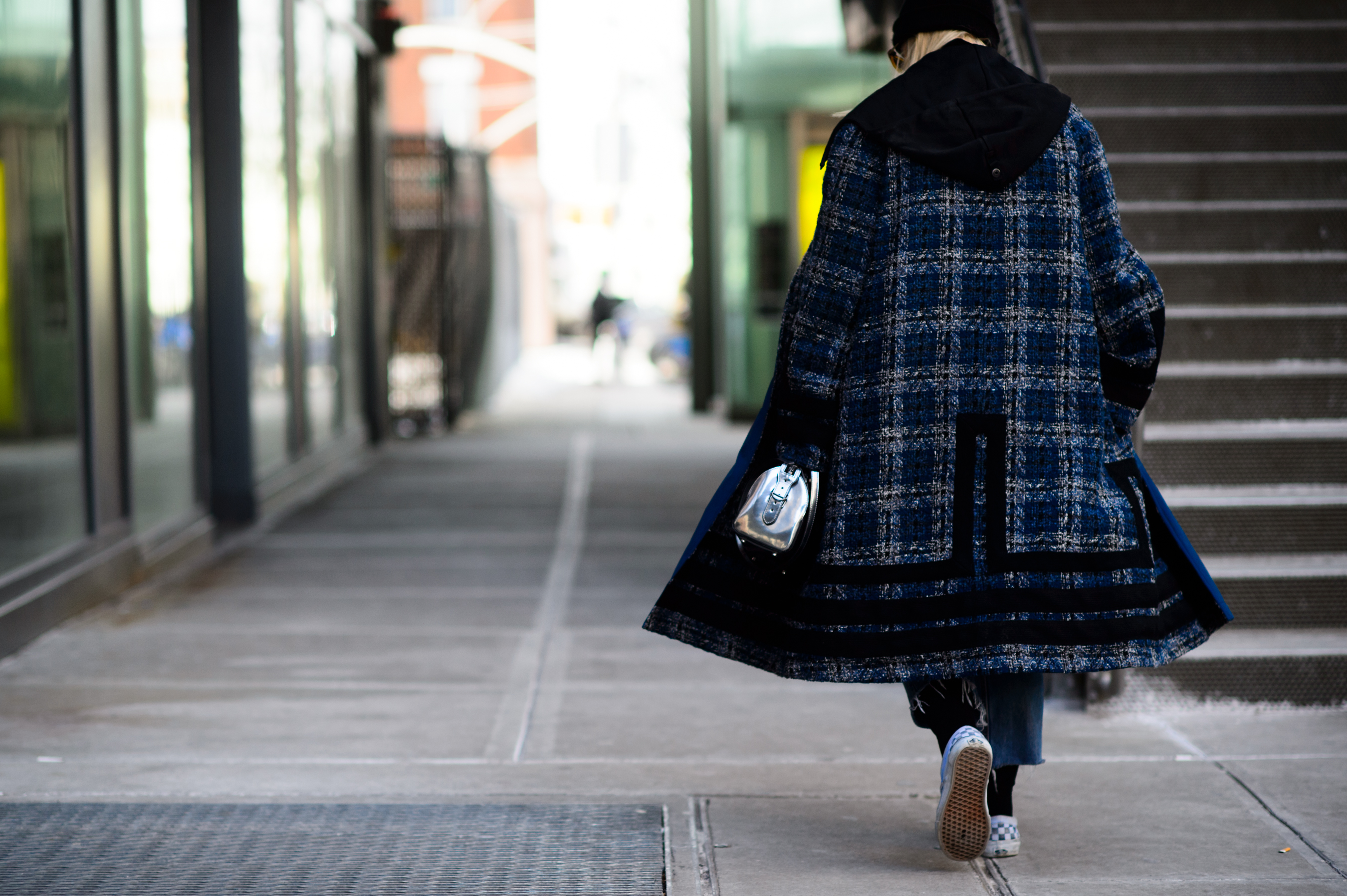 Woman wearing big blue coat and slip ons