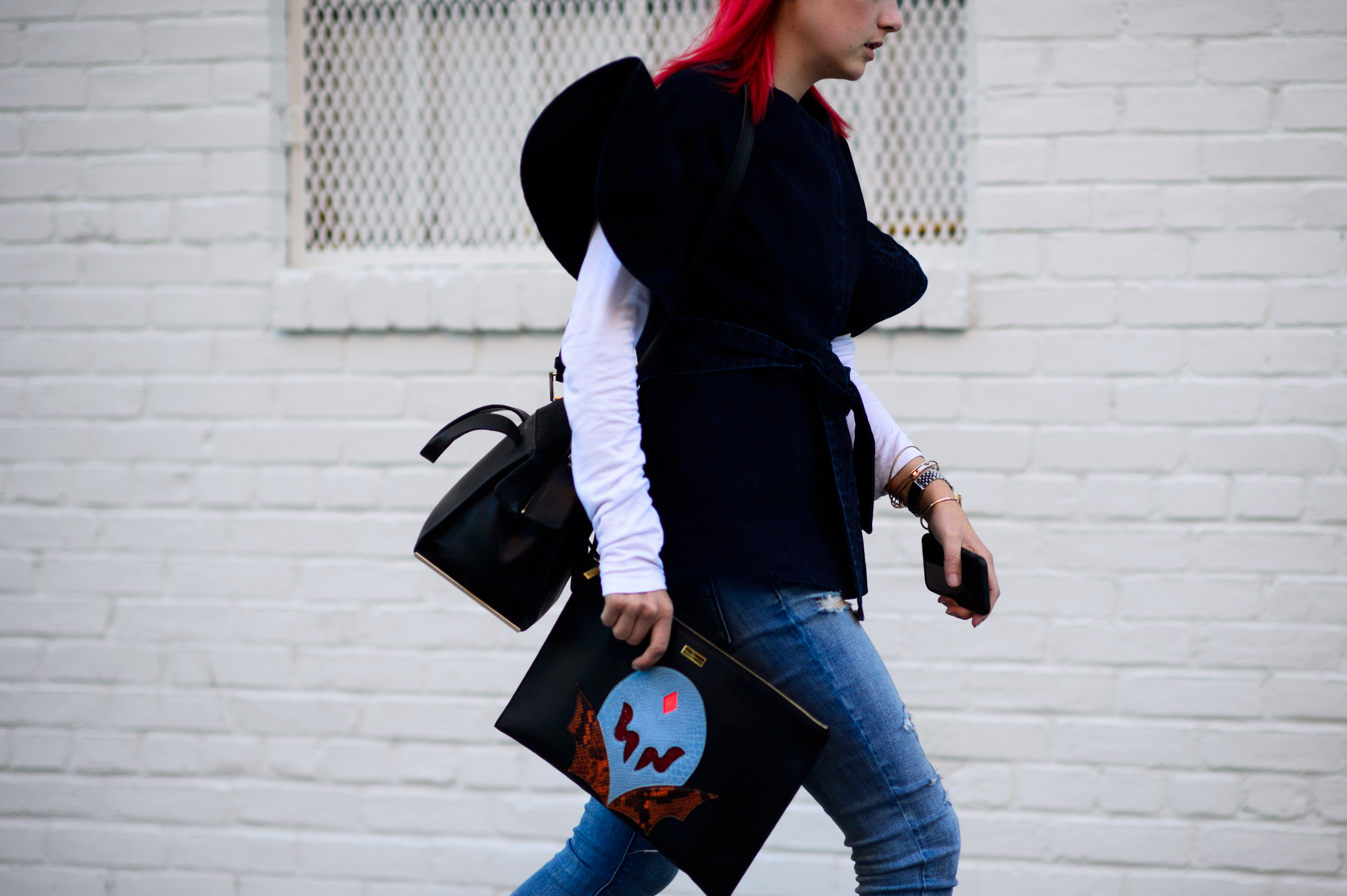 Woman in black vest with clutch bag