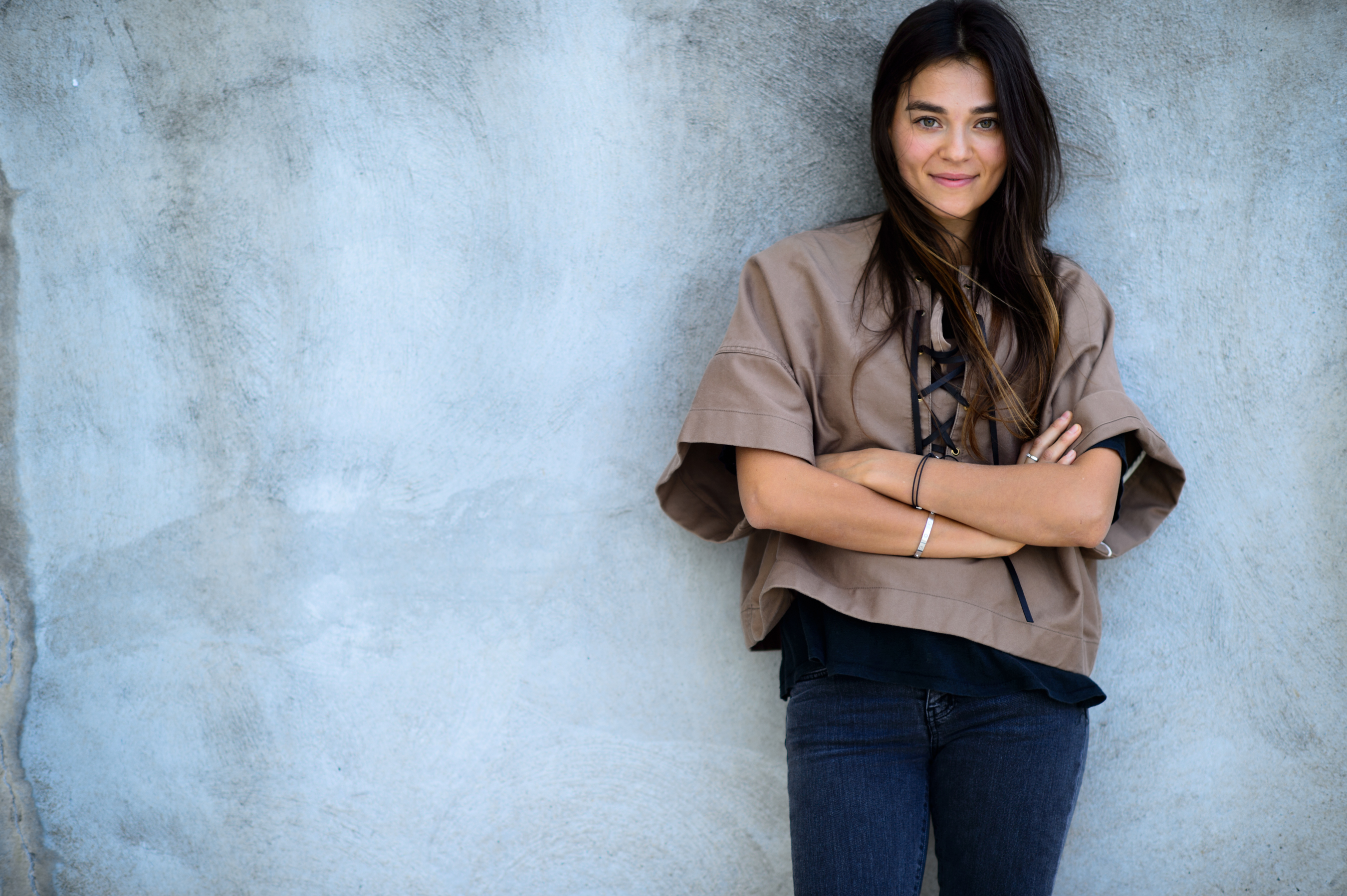 Woman posing in front of the gray wall