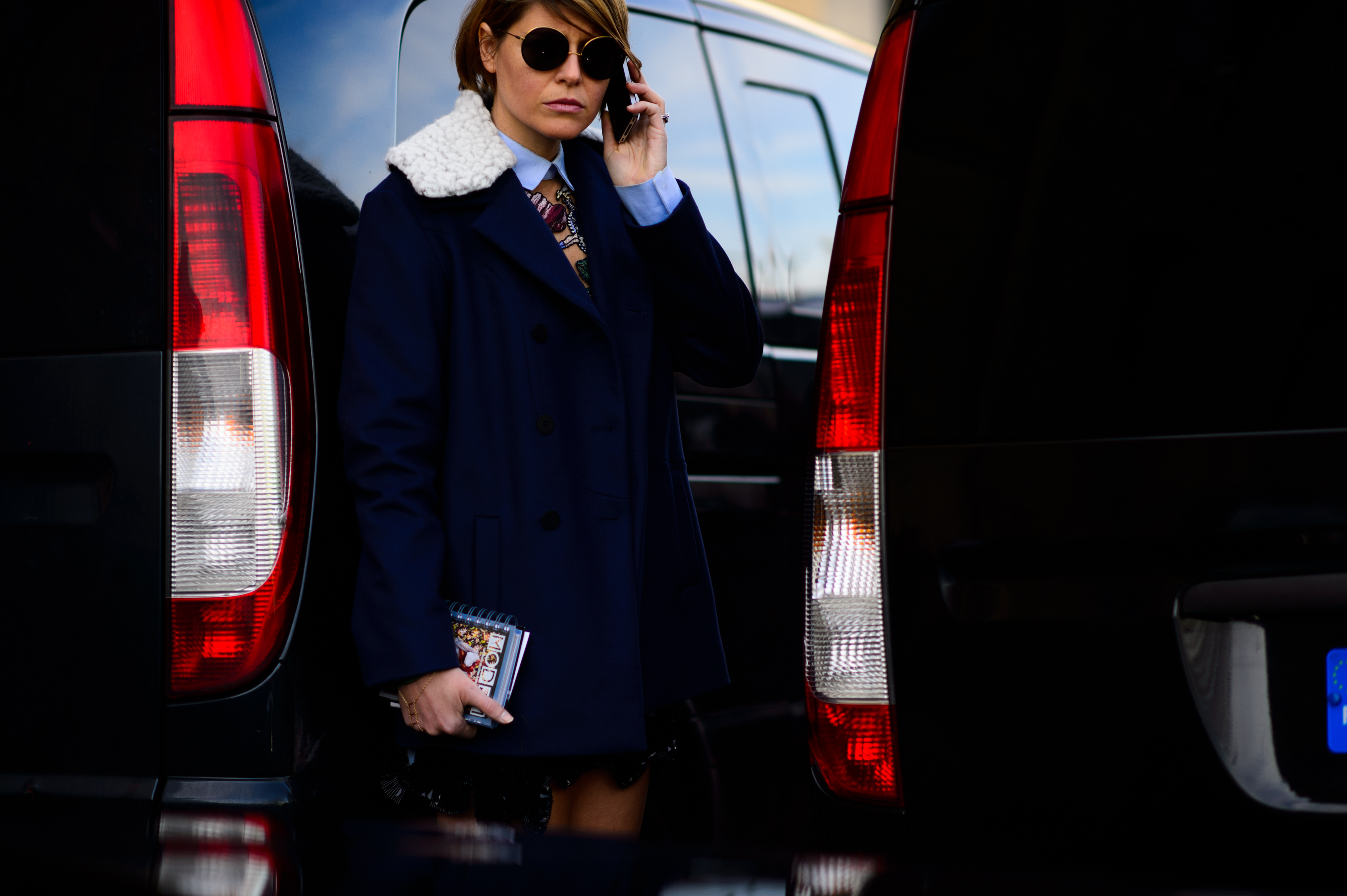 Woman wearing blue outfit stands between the cars