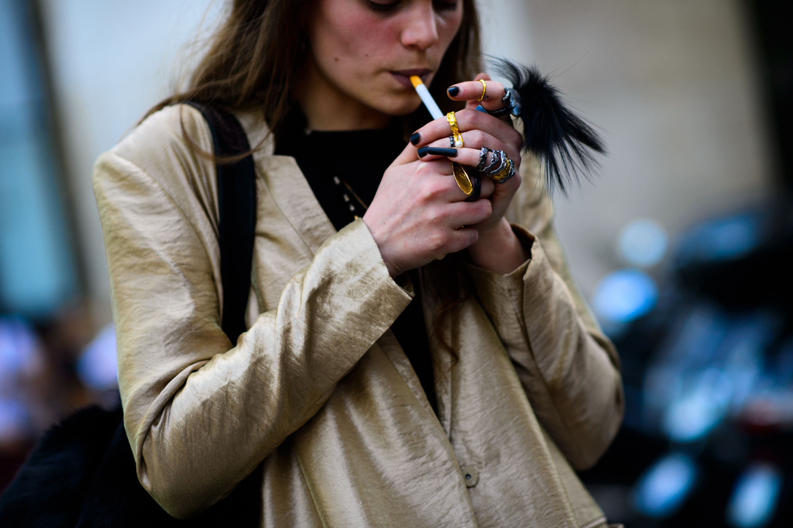 Woman wearing a lot of rings lighting up a cigarette