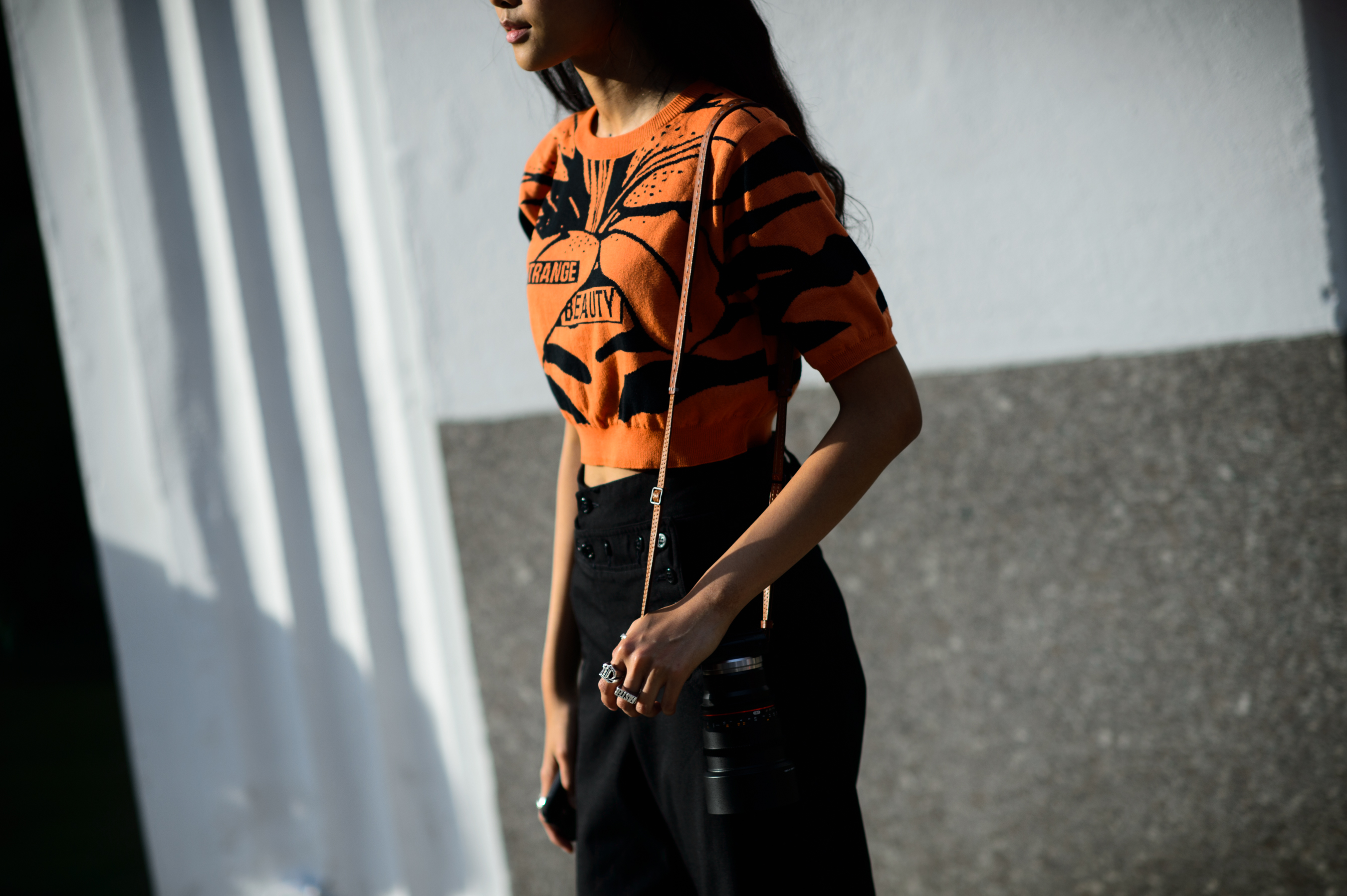 Woman wearing short orange sweater and a skirt