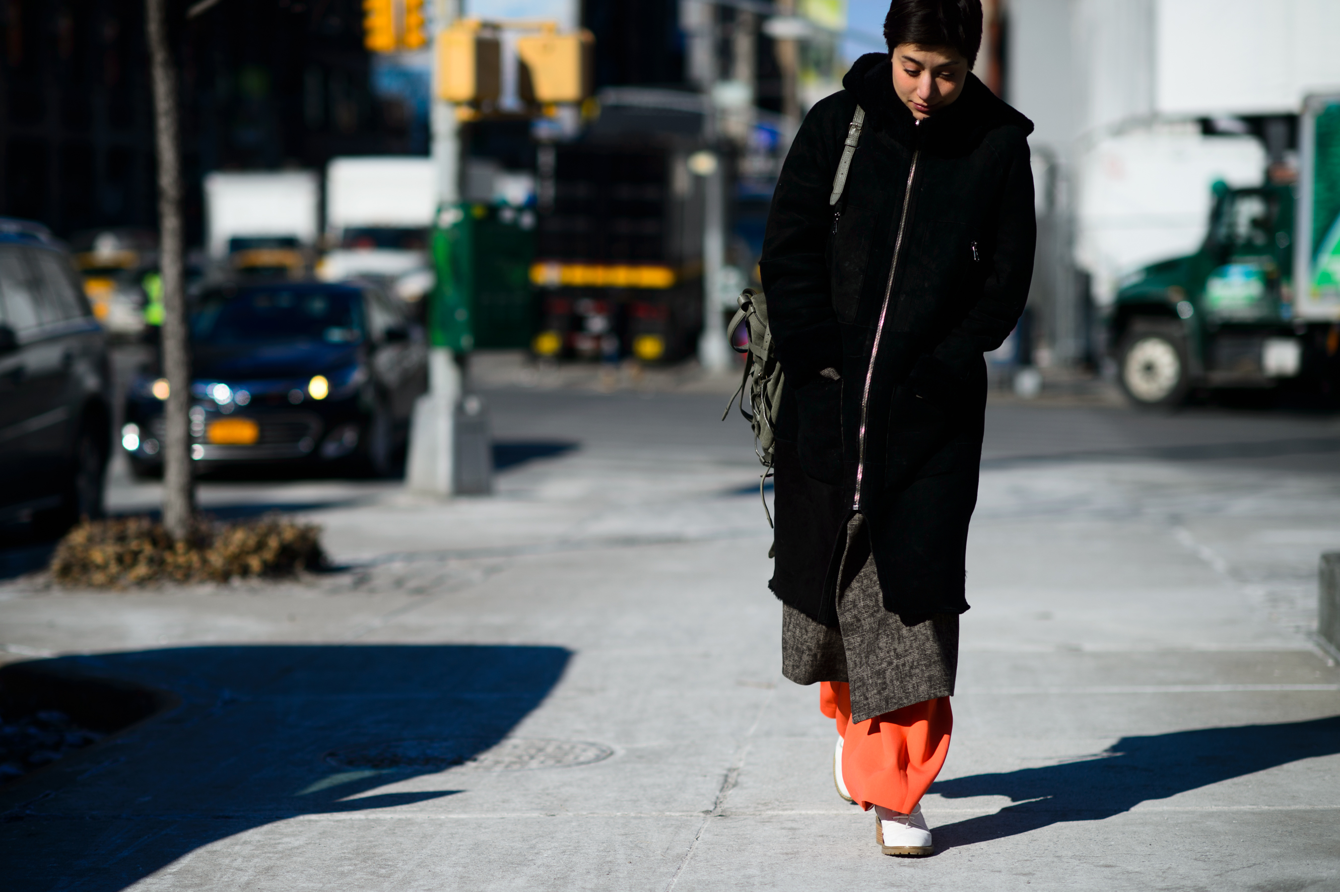 Woman wearing orange pants and black coat