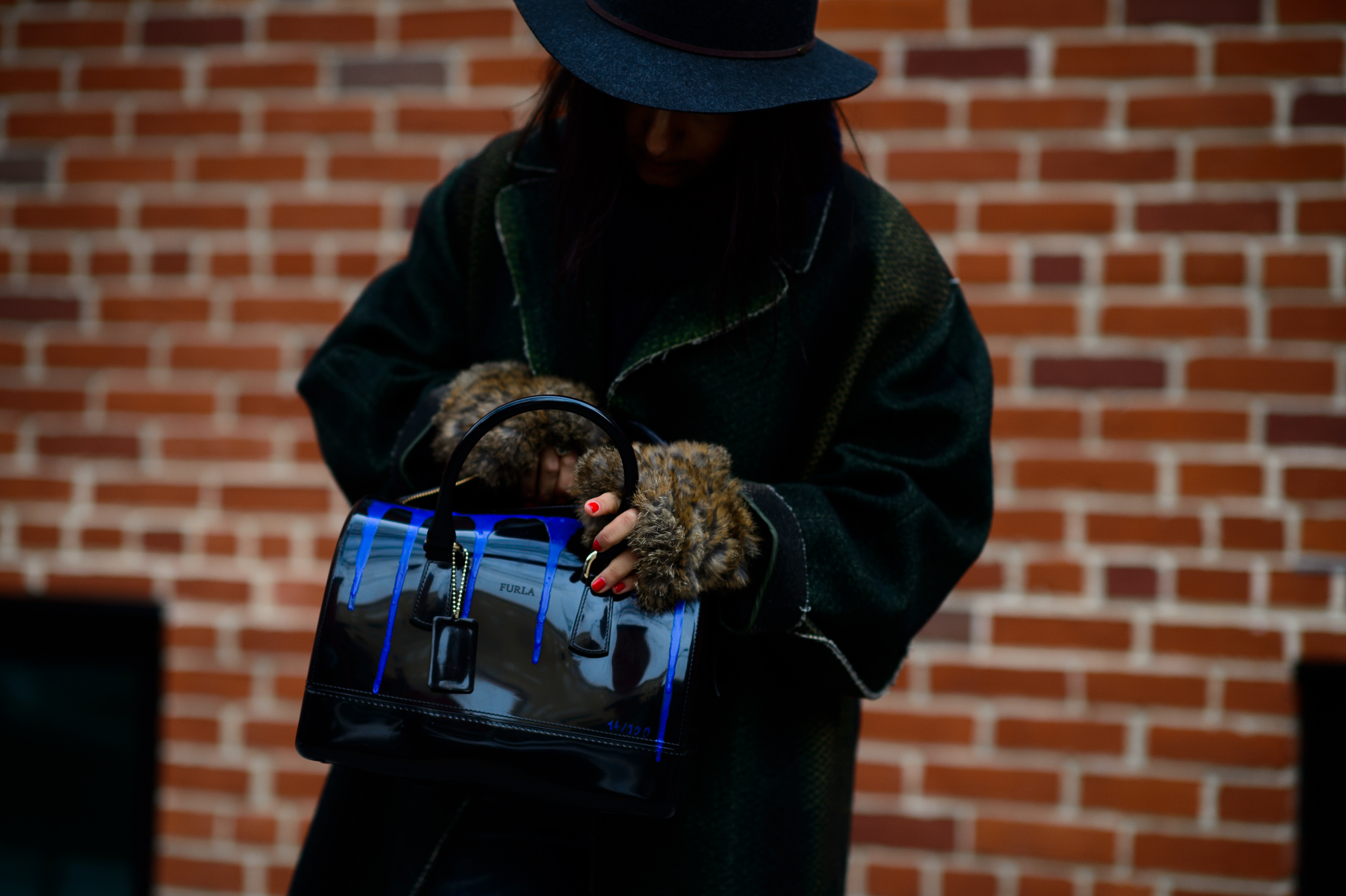 Woman wearing hat and black bag with blue detail