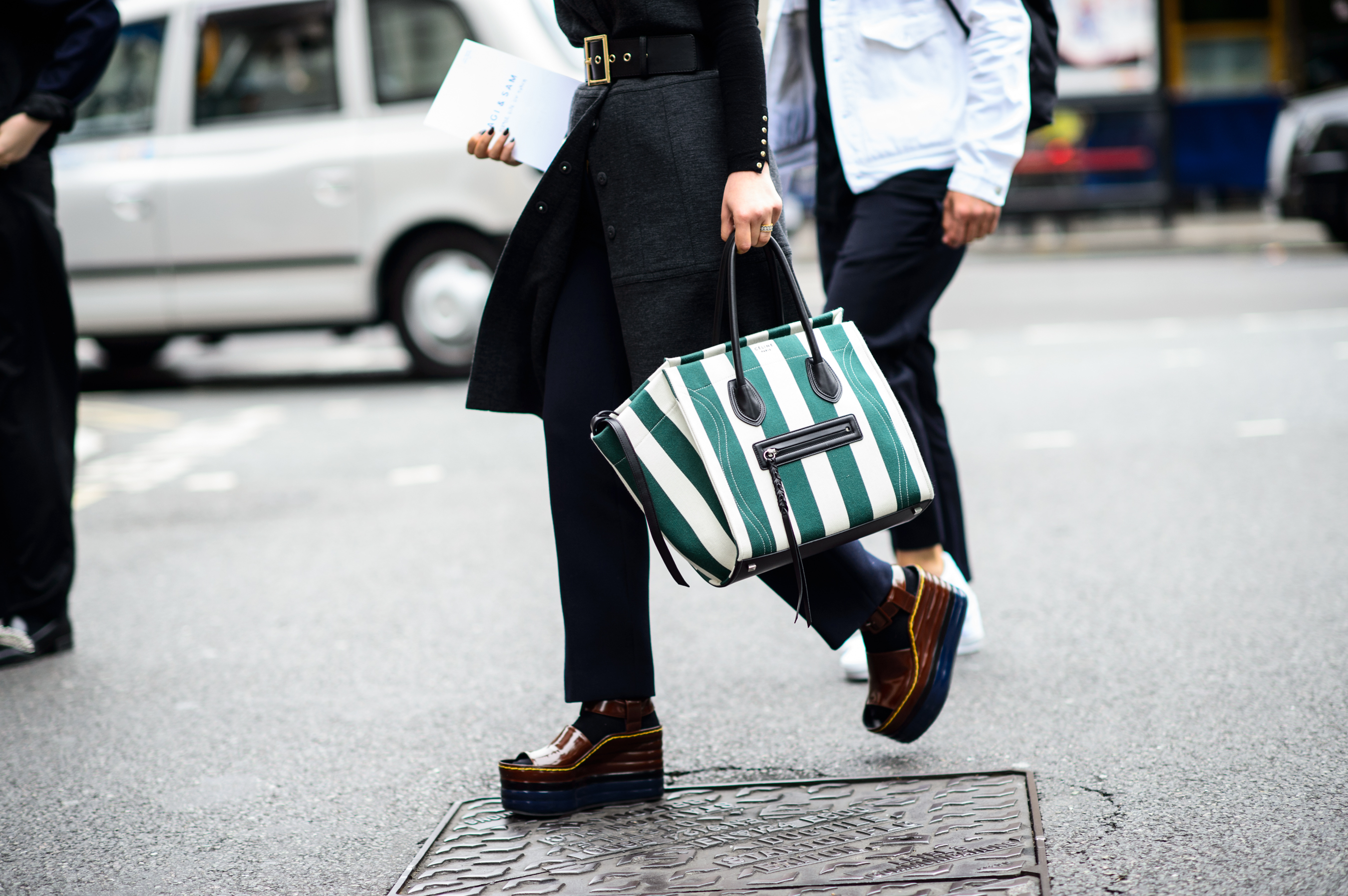 Woman crossing the road with green bag and wedges