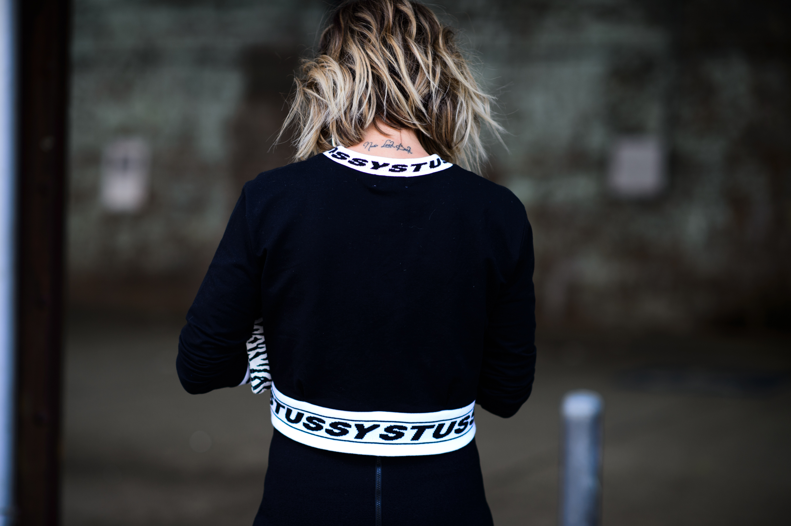 Woman wearing black outfit with white stripes with letters on them