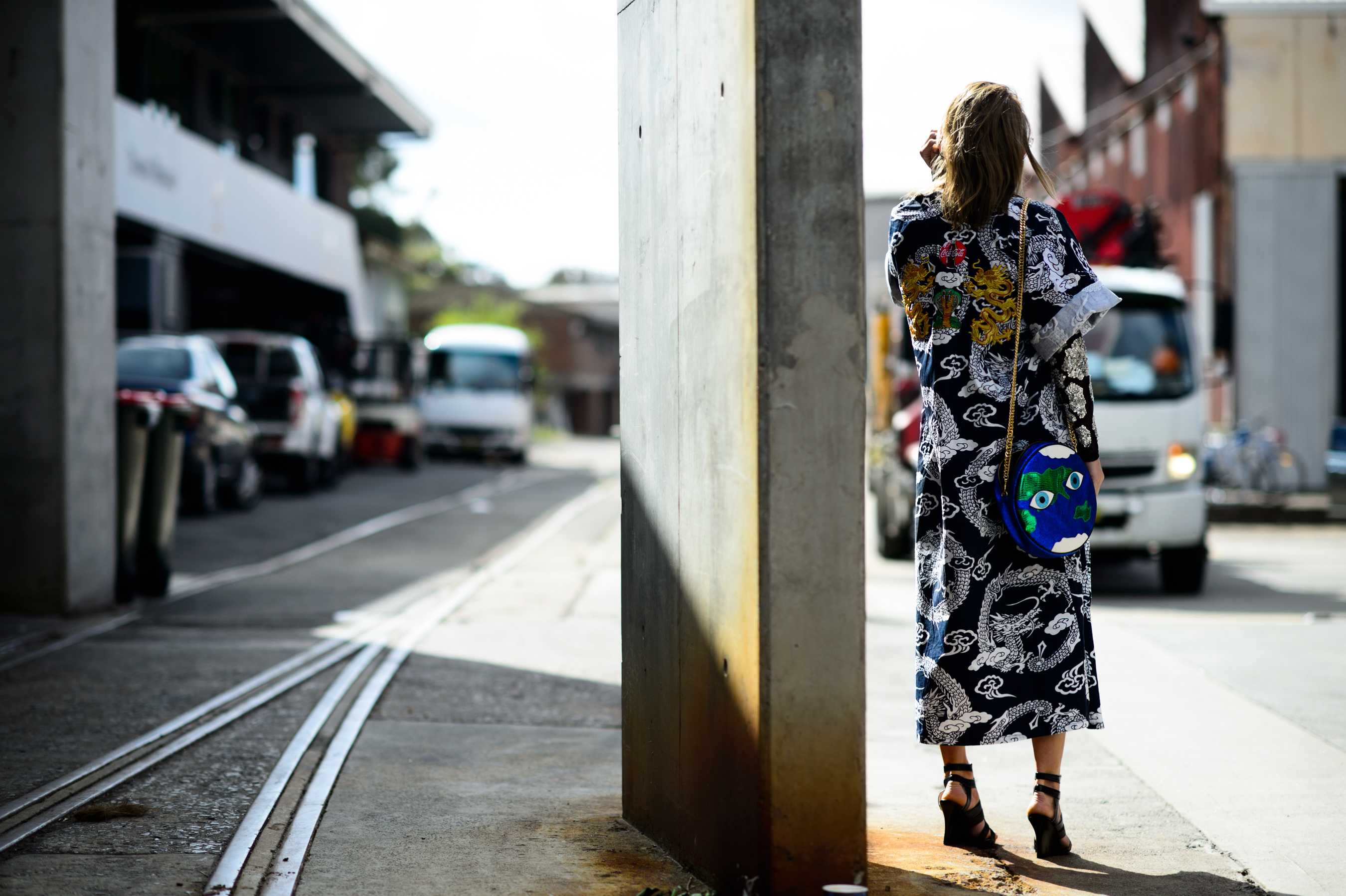 Woman wearing kimono style coat and bag shaped like Earth