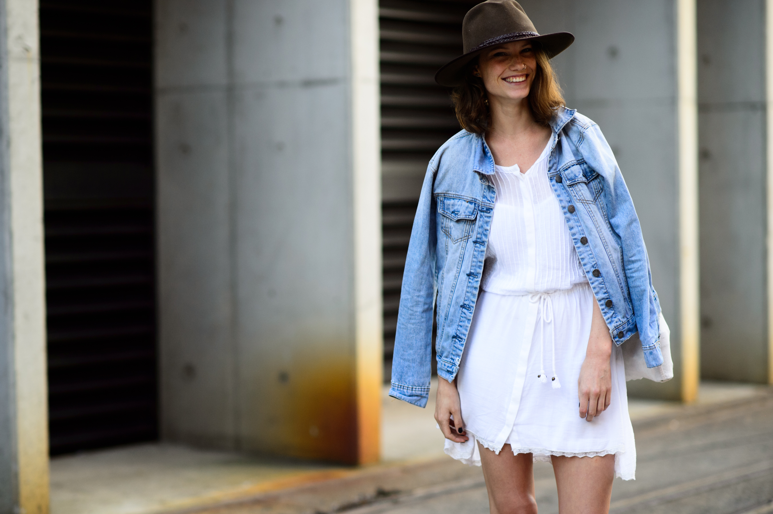 Woman wearing white cotton dress, hat and a denim jacket