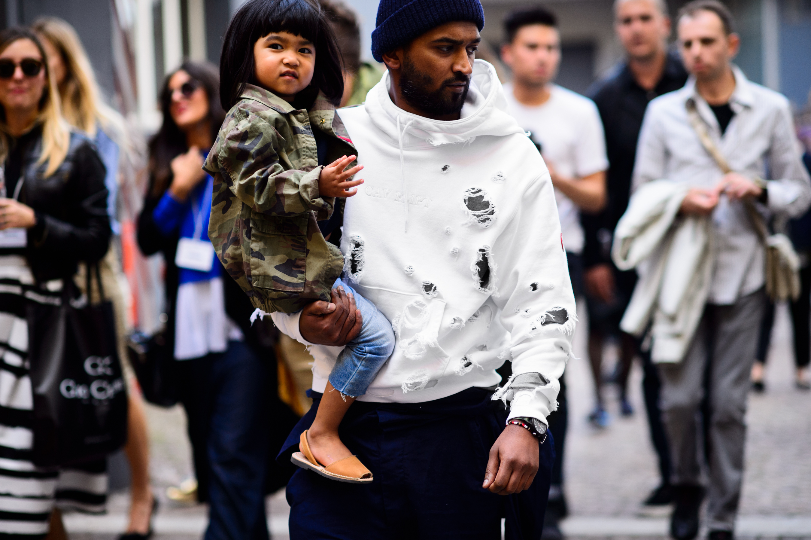 Man in ripped sweatshirt carrying his child