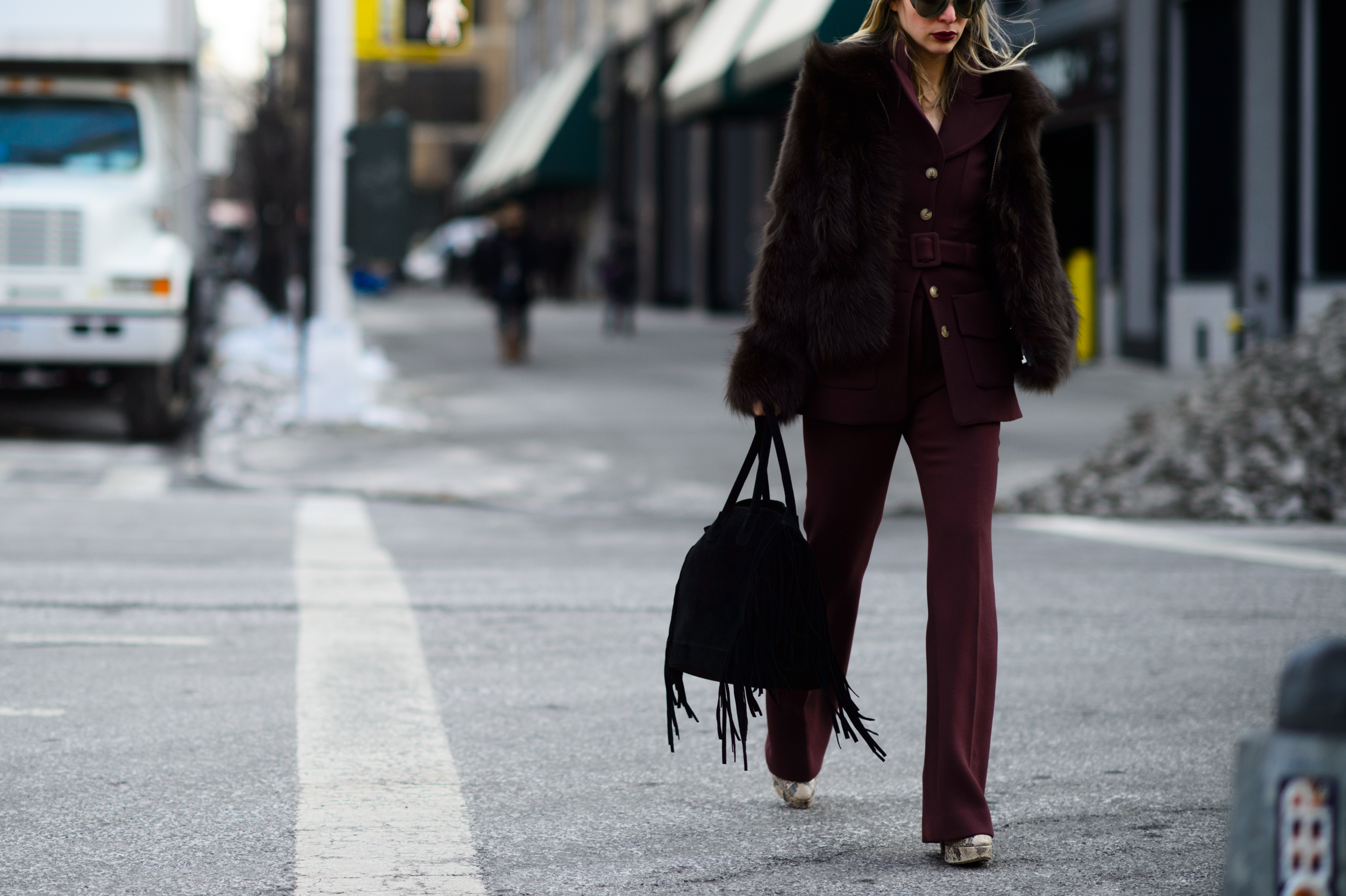 Woman wearing bordeaux suit crosses the road