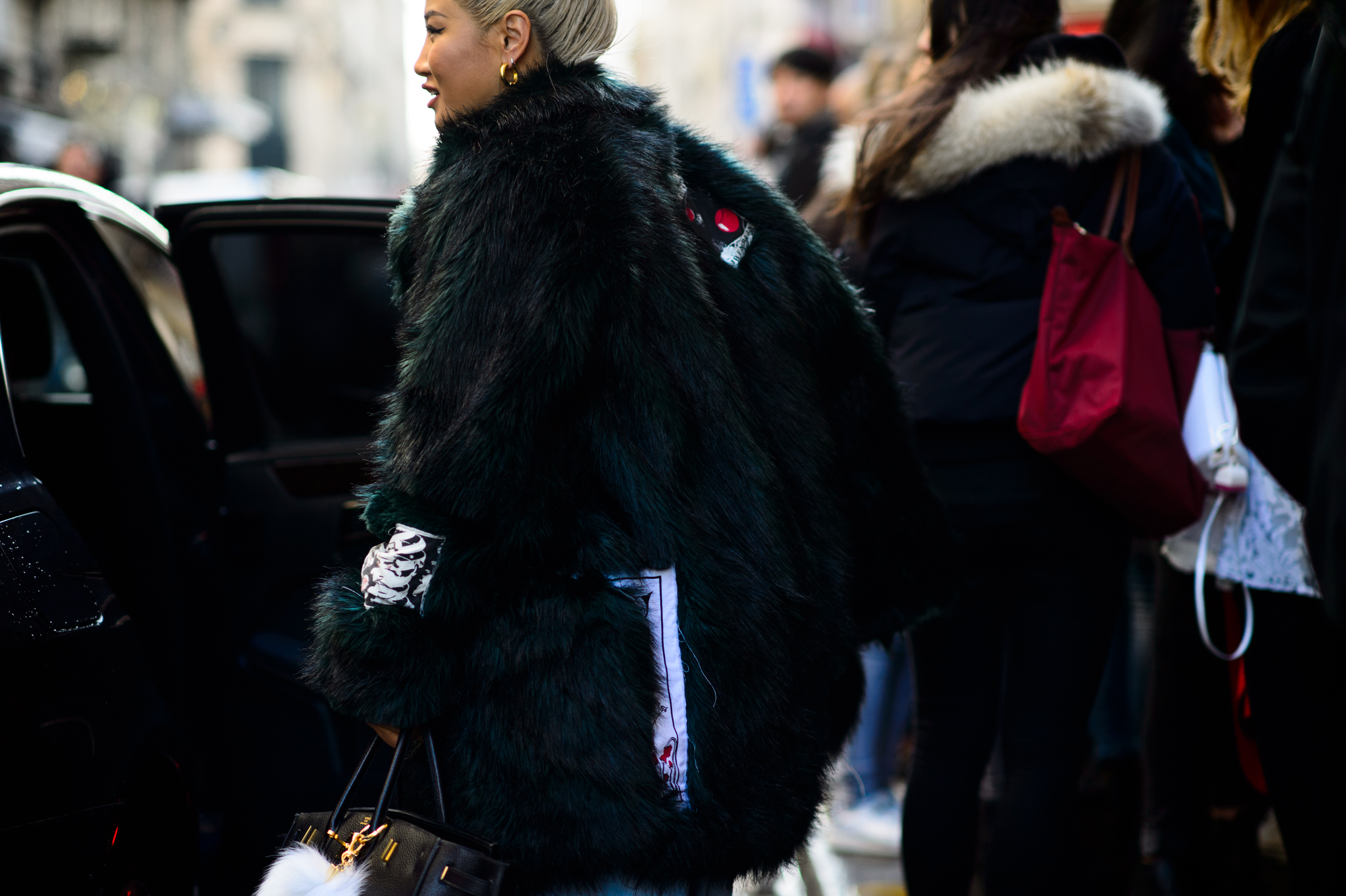 Woman wearing green fur coat getting in the car