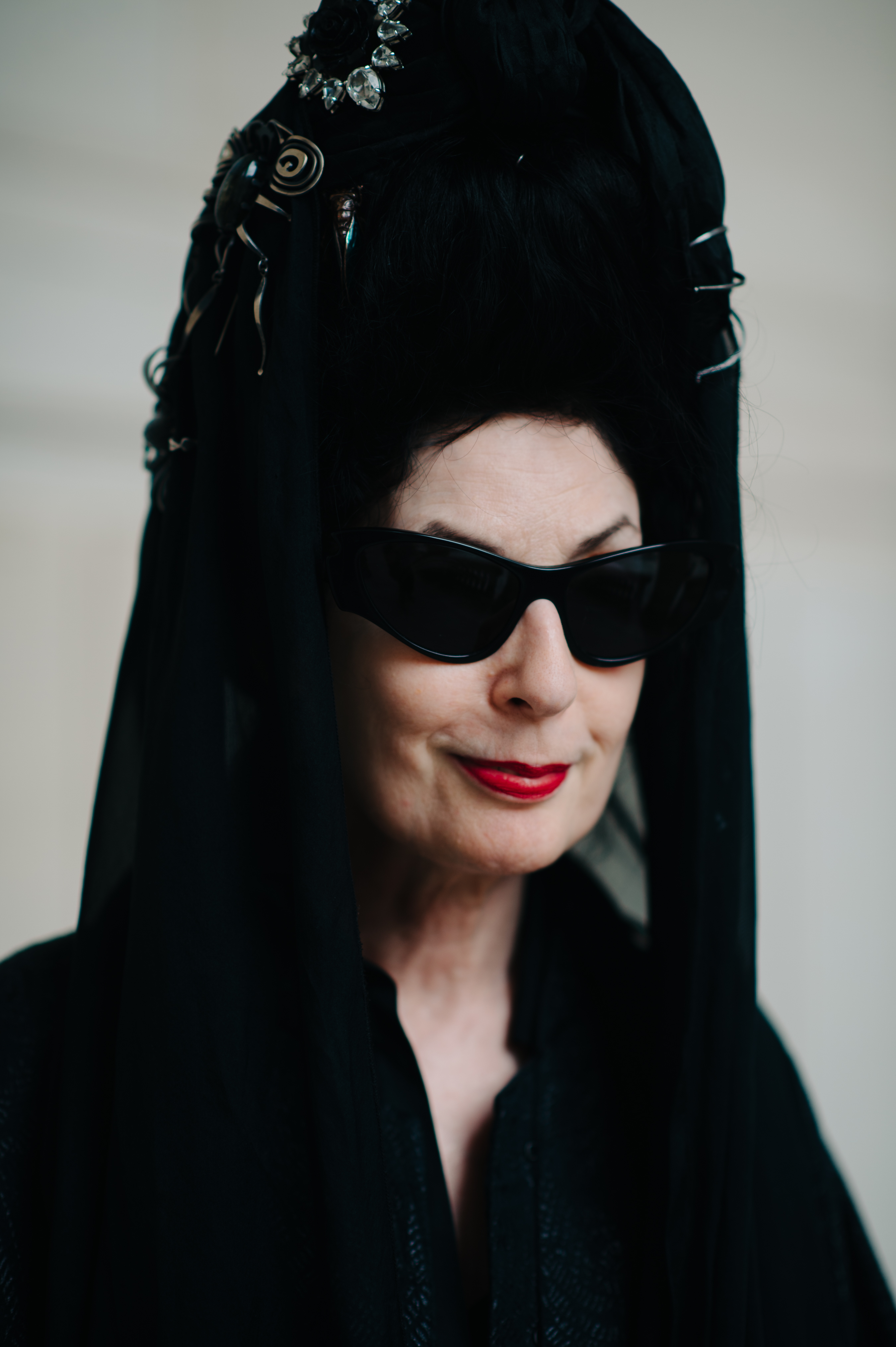 Portrait of a woman wearing black headpiece with spiders and glasses