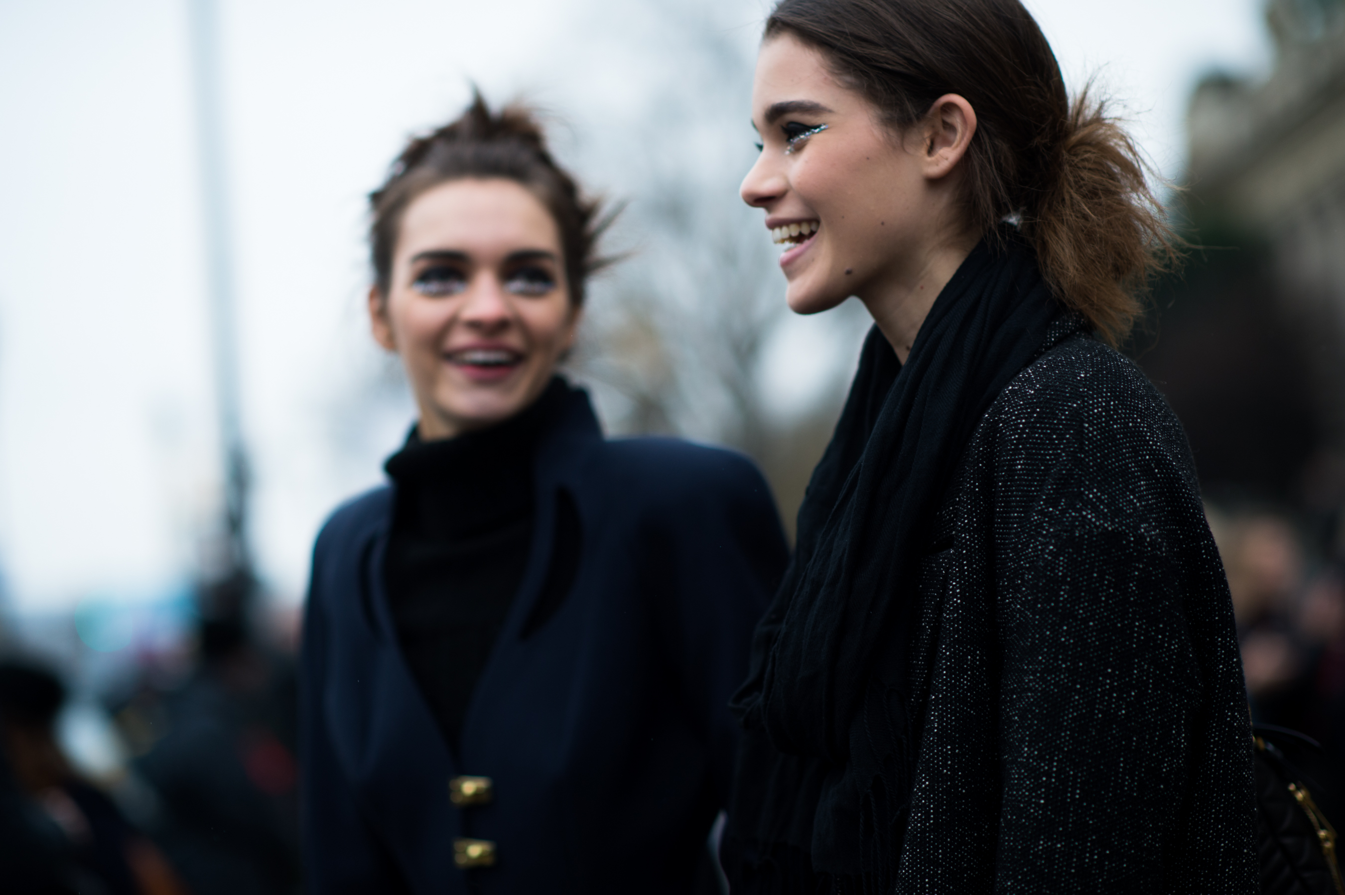 Two models wearing shiny make up after the show