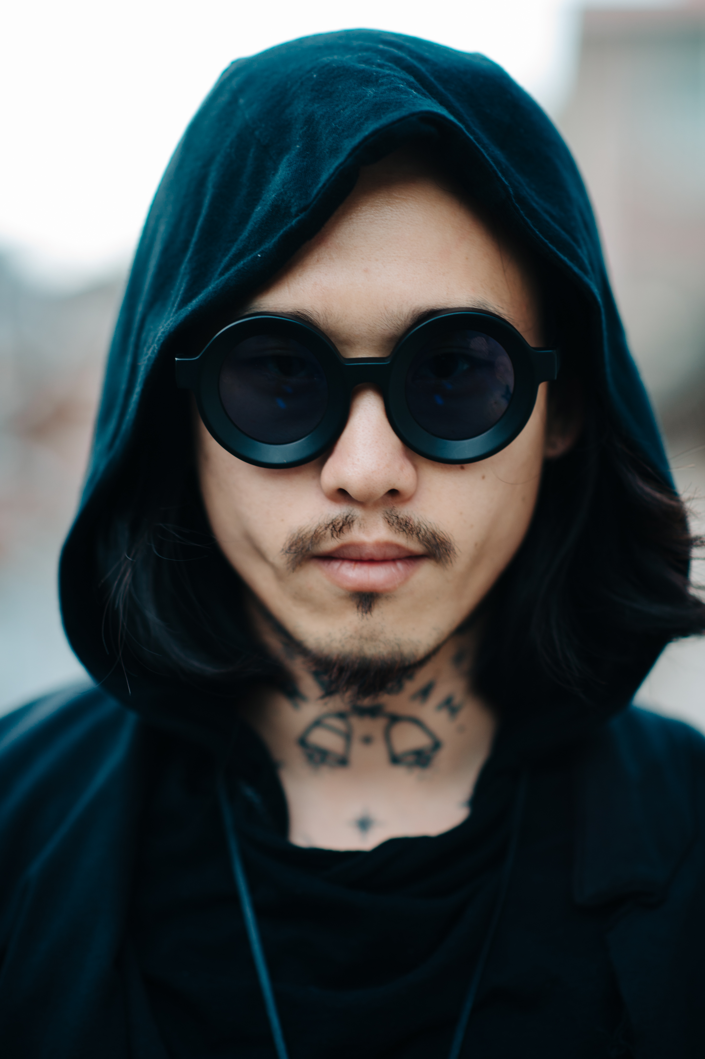 Portrait of a Korean tattoo artist wearing glasses and hood