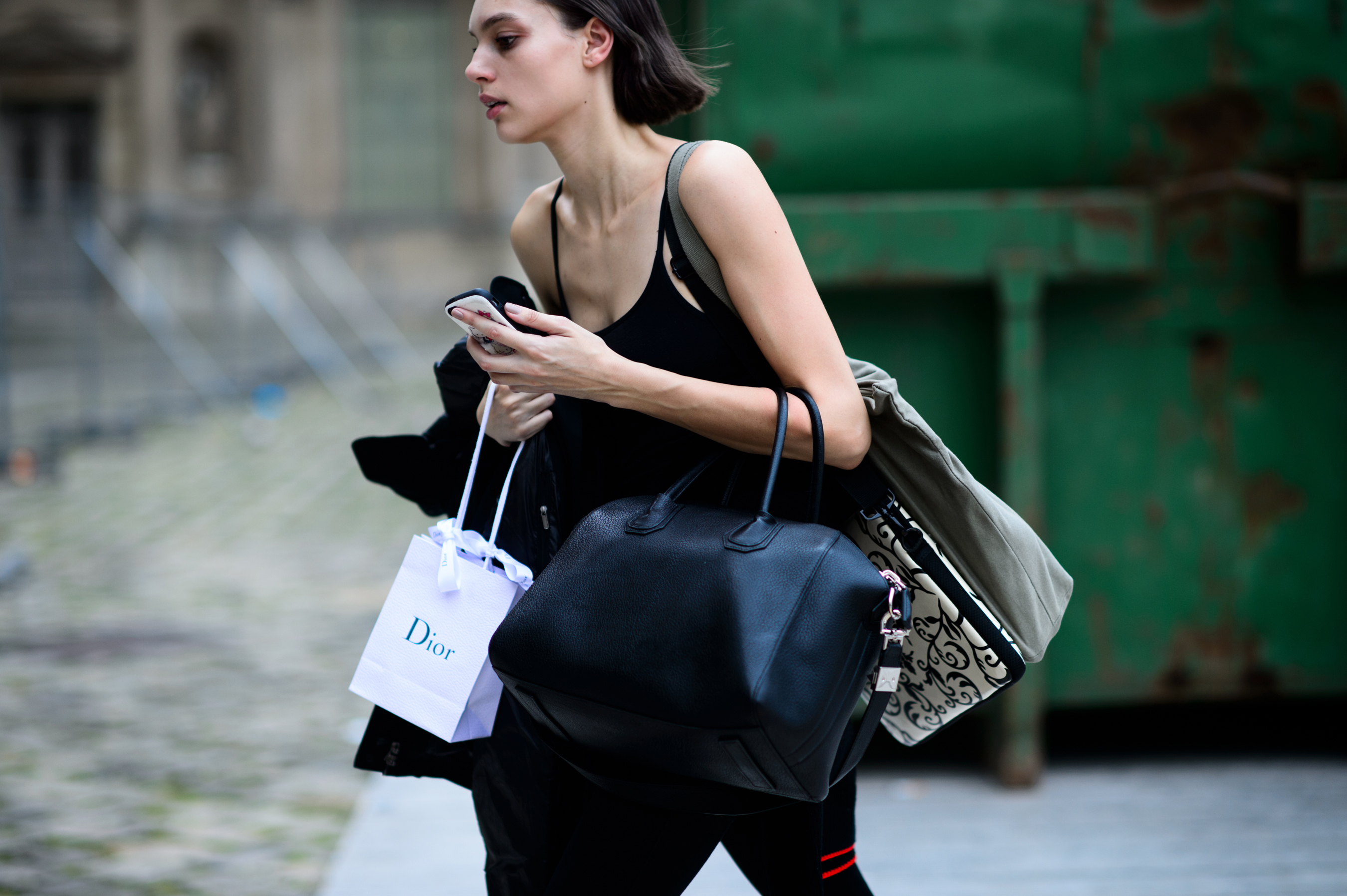 Model in black vest holding several bags