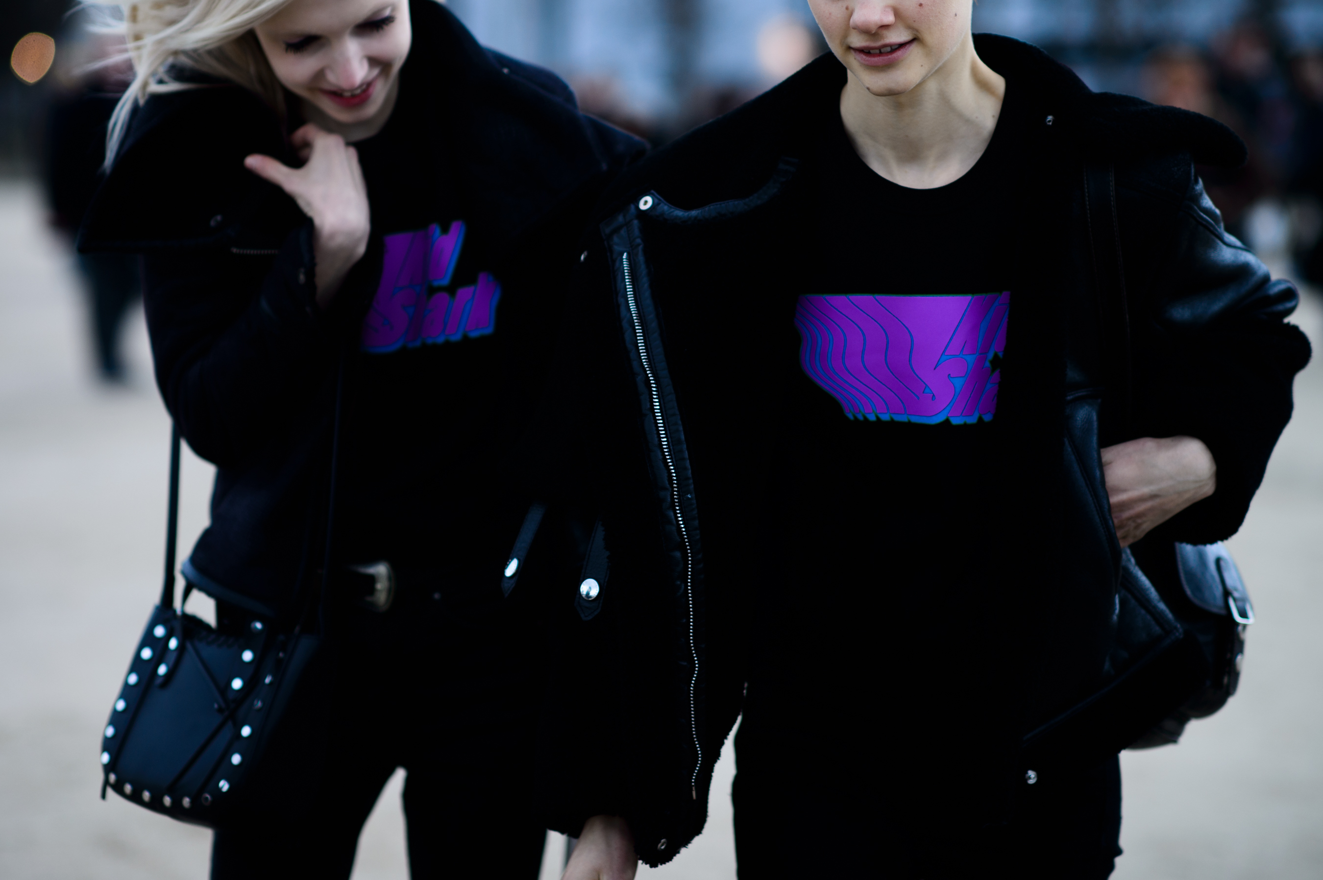 Two models wearing black and purple graphics