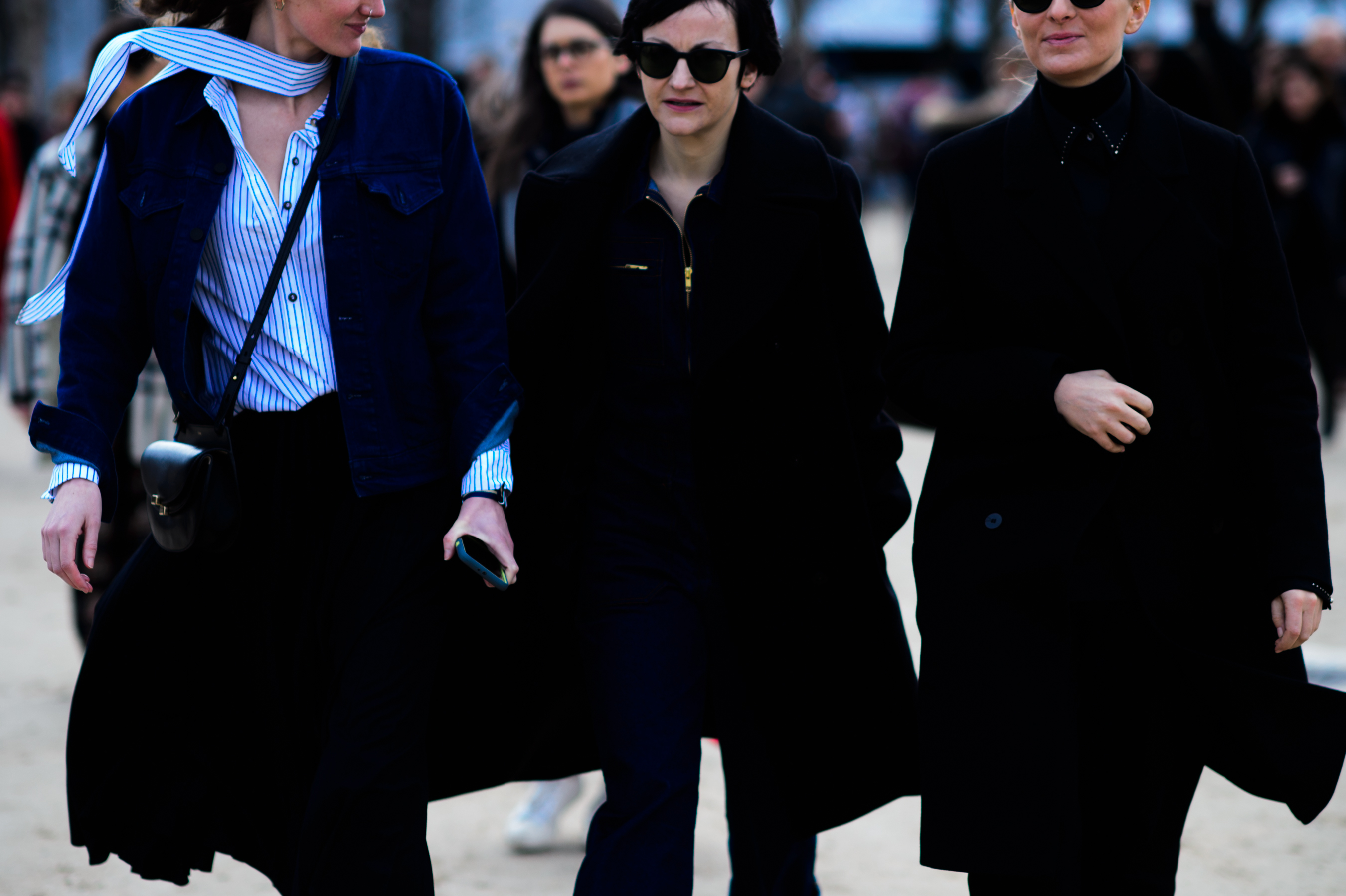 Three women wearing dark coats leave show