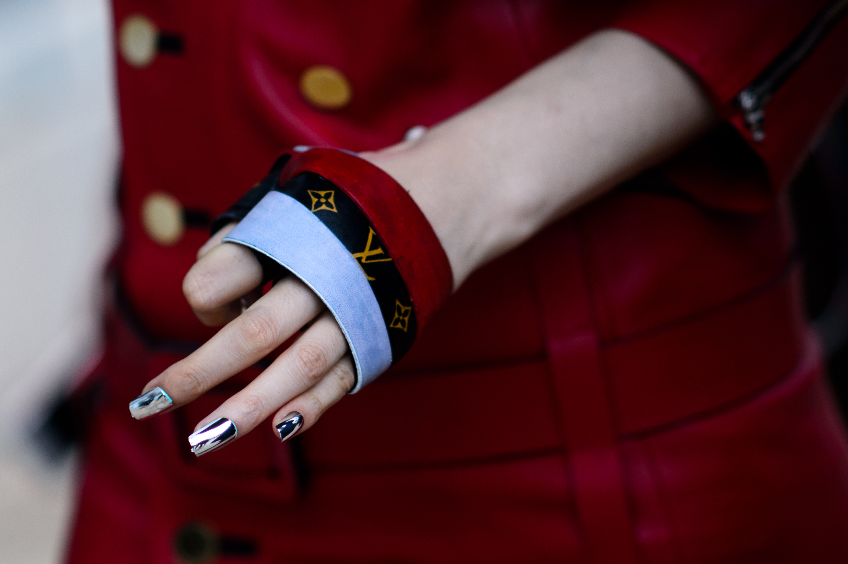 Closeup of womans hand with silver nail polish and glove