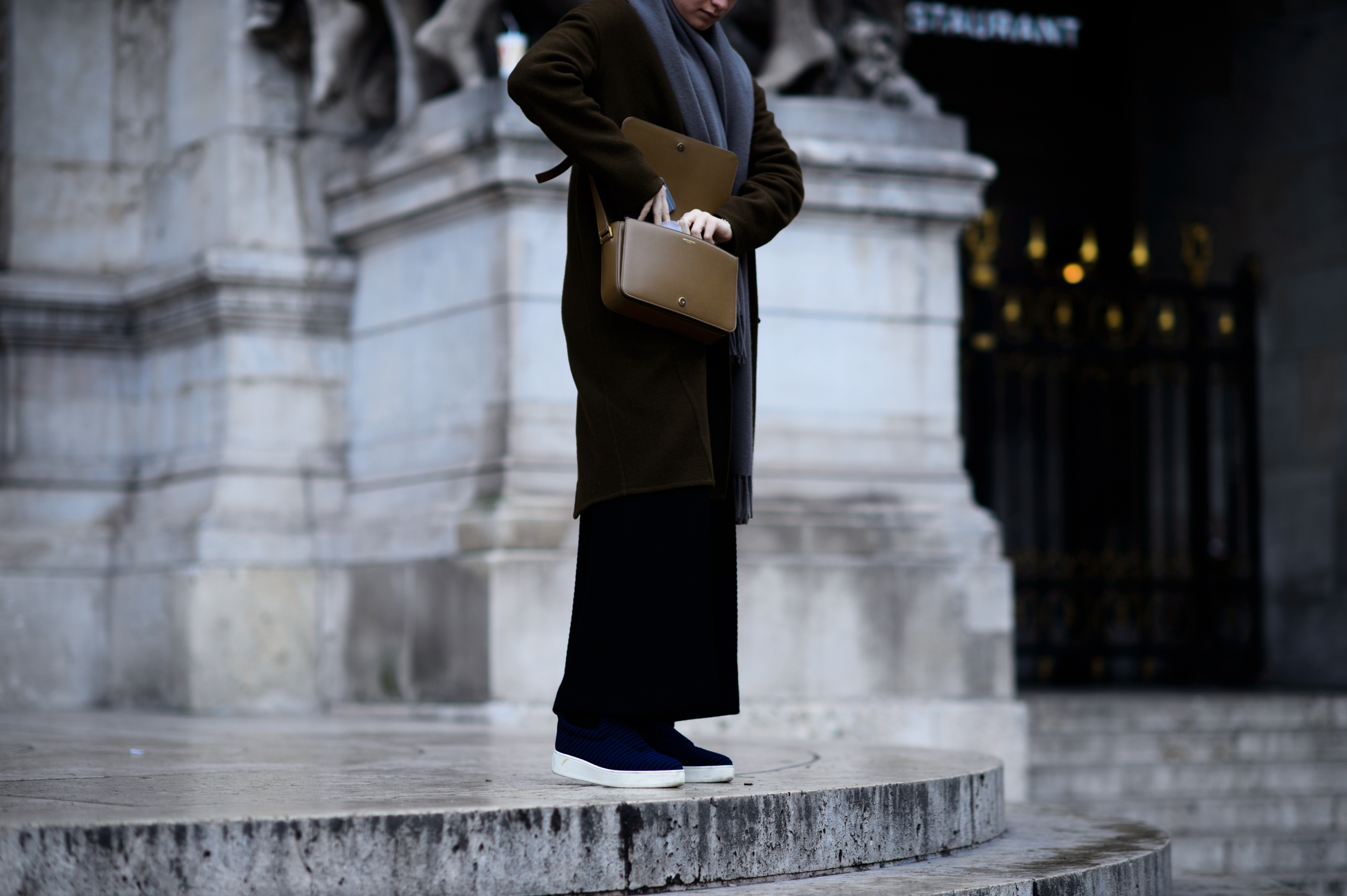 Woman stood on steps reaching into brown purse